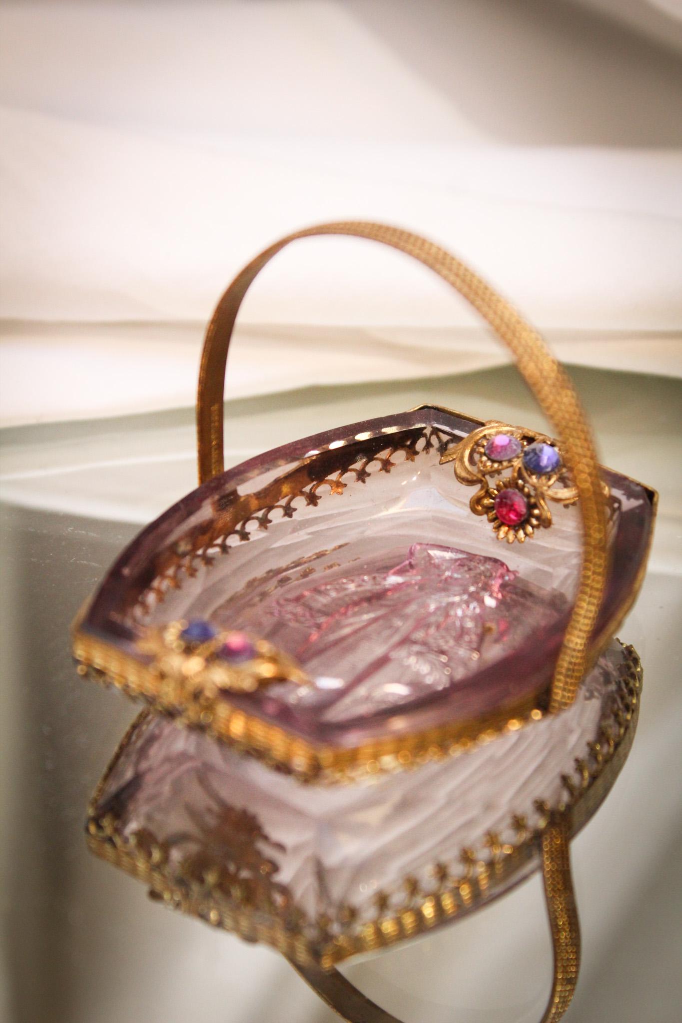 Czechoslovakian Amythest Intaglio Glass Jeweled Salt Dip: What a sweet piece this is folks. An amythest Czech glass intaglio salt dip nestled in a jeweled frame. Jewels are in shades of purples and pinks. Nice!. It measures 2" tall, 2 1/2" wide. Put this at 