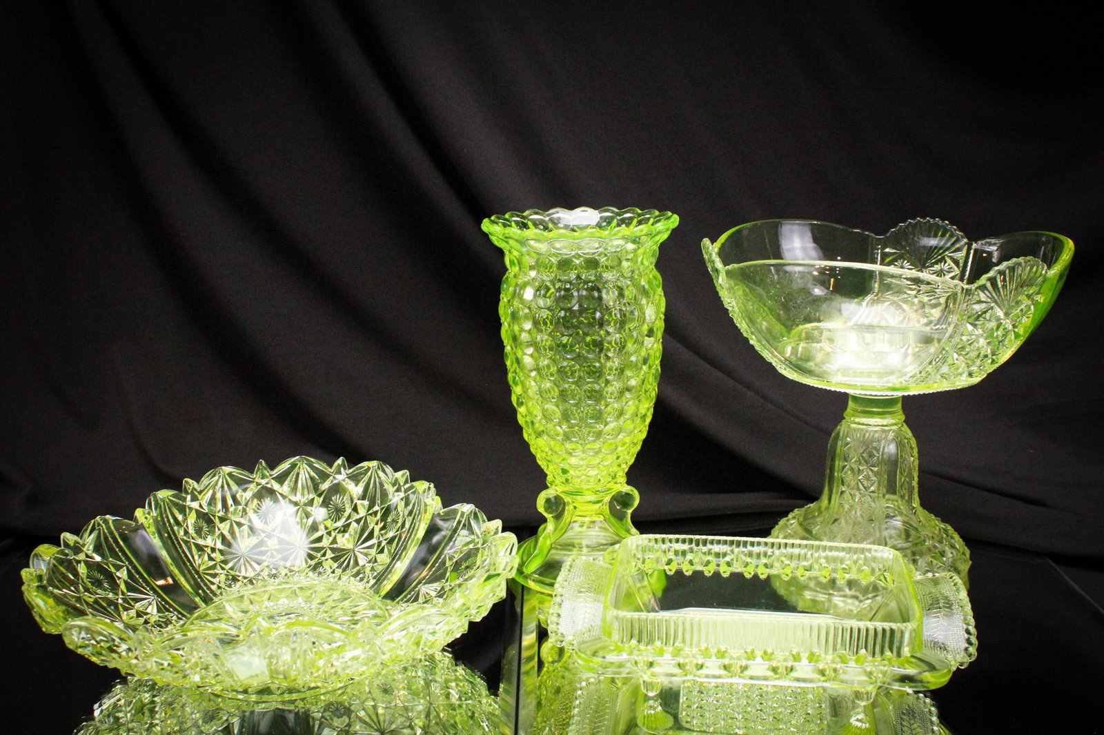 4 pc Lot Victorian Vaseline Glass: Select offering here of 4 nice pieces of uranium Victorian glass. Lot is represented by a compote, a celery vase, a bowl, and a dish lacking lid. Tallest measures 8 1/2".