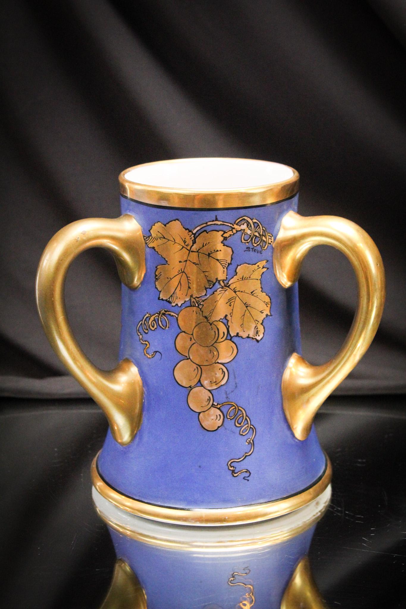 Limoges Hand Painted Porcelain Loving Cup: Signed J.P.L. France Limoges loving cup expertly hand painted with grapes and gilt decoration. It measures 7 1/2" tall.