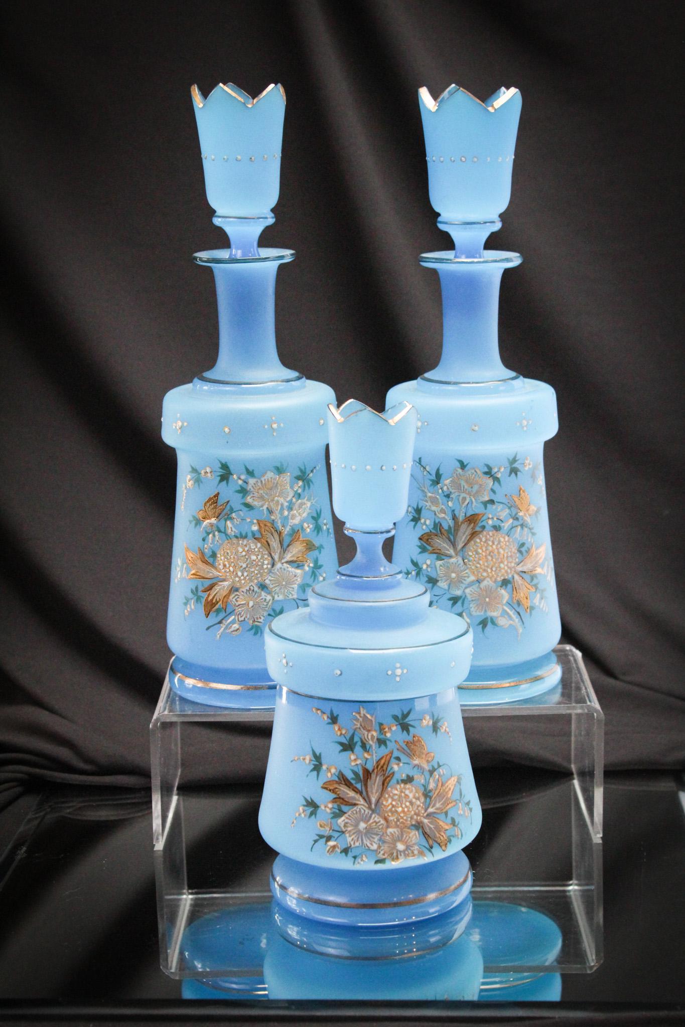 3 pc Victorian Blue Bristol Glass Vanity Cologne Dresser Set: Radiant blue clambroth glass enameled and gilt decorated 3 piece cologne bottle vanity set. The bottles glisten with the beautiful decoration and the abundance of gold. Tallest measures 10 3/4".