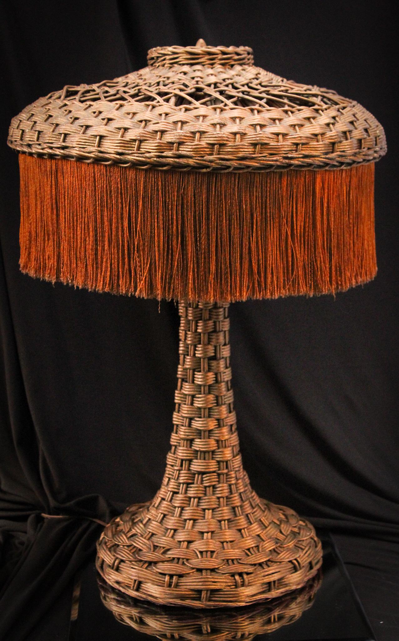 Antique Wicker Art Deco Table Lamp: Wonderful original condition dating to the 1900's to 1920's wicker Art Deco period table lamp. Lamp is complete with the original silk fringe and lining. Very nice example. It measures 25" tall.