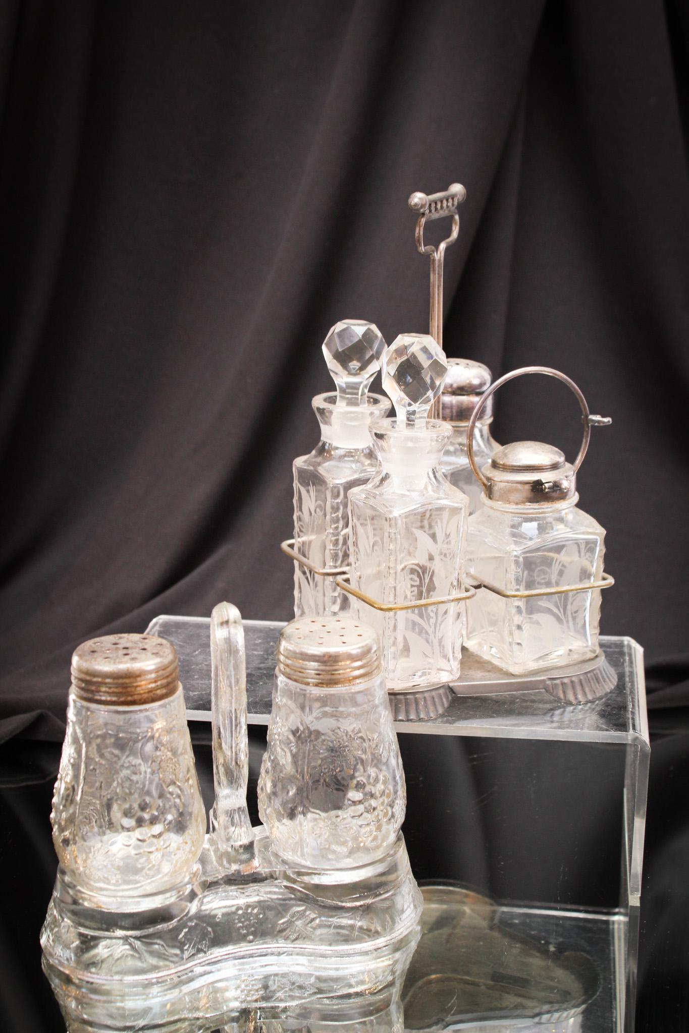 2 pc Lot Victorian Salt Shaker Silverplate Condiment Sets: Two great shakers sets are offered together in this lot. One is a pair of grape embossed glass shakers complete with glass caddy. The other is a Pairpoint set in signed Pairpoint silverplate holder. B