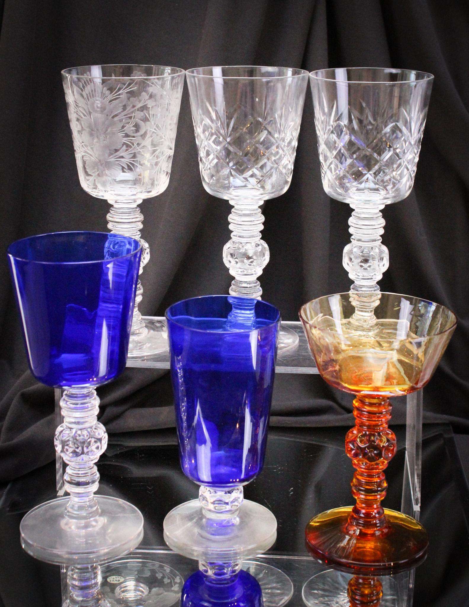 6 pc Lot Heisey Glass Spanish Stemware: Spanish stemware at its finest. Lot is comprised of three engraved water goblets, one cobalt goblet, one cobalt tumbler, and one amber stem. Tallest measures 7 1/2".