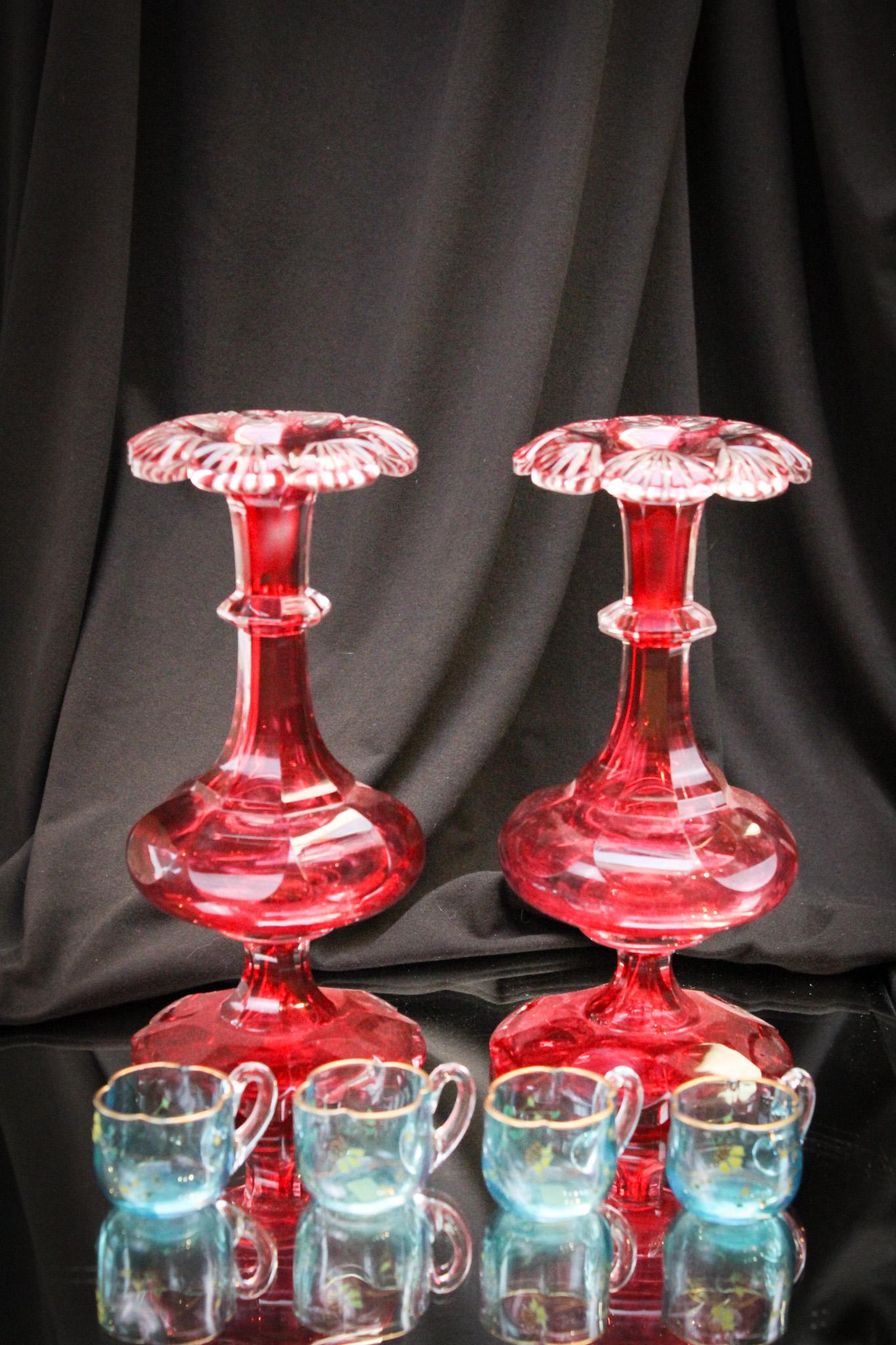 Pair of Ruby Cut Glass Vases & 4 Enameled Cordials: Select offering of a pair of ruby cut Bohemian vases paired with a set of 4 Bohemian Prussian blue enameled cordials. Vases measures 8 1/4" tall. Lovely.