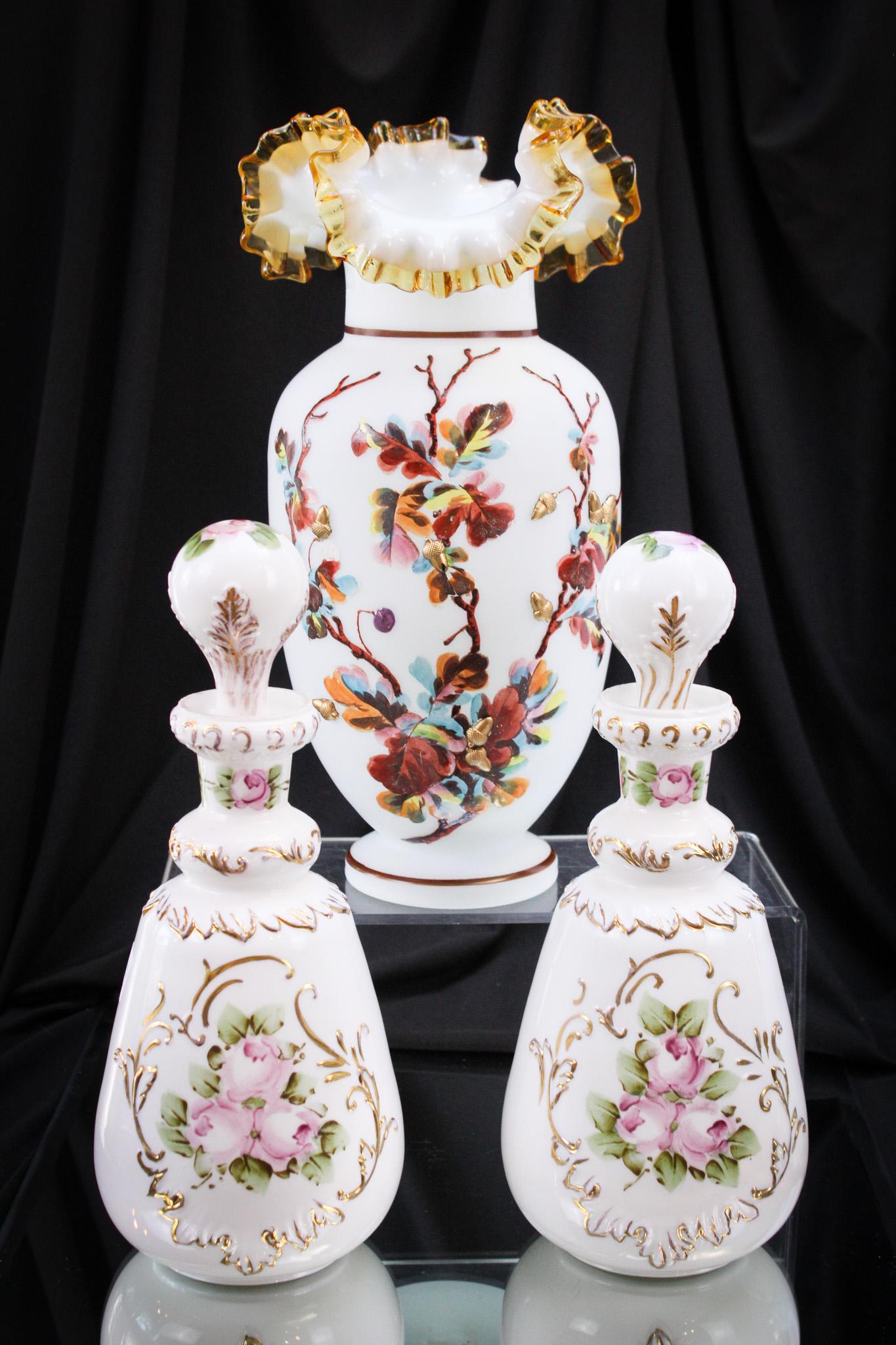 3 pc Lot Victorian Enameled Art Glass: Lovely offering of three fine pieces of Victorian Glass comprised of a pair of dresser cologne vanity bottles and a large vase with amber applied edge and enameled and applied acorn decoration. Talles
