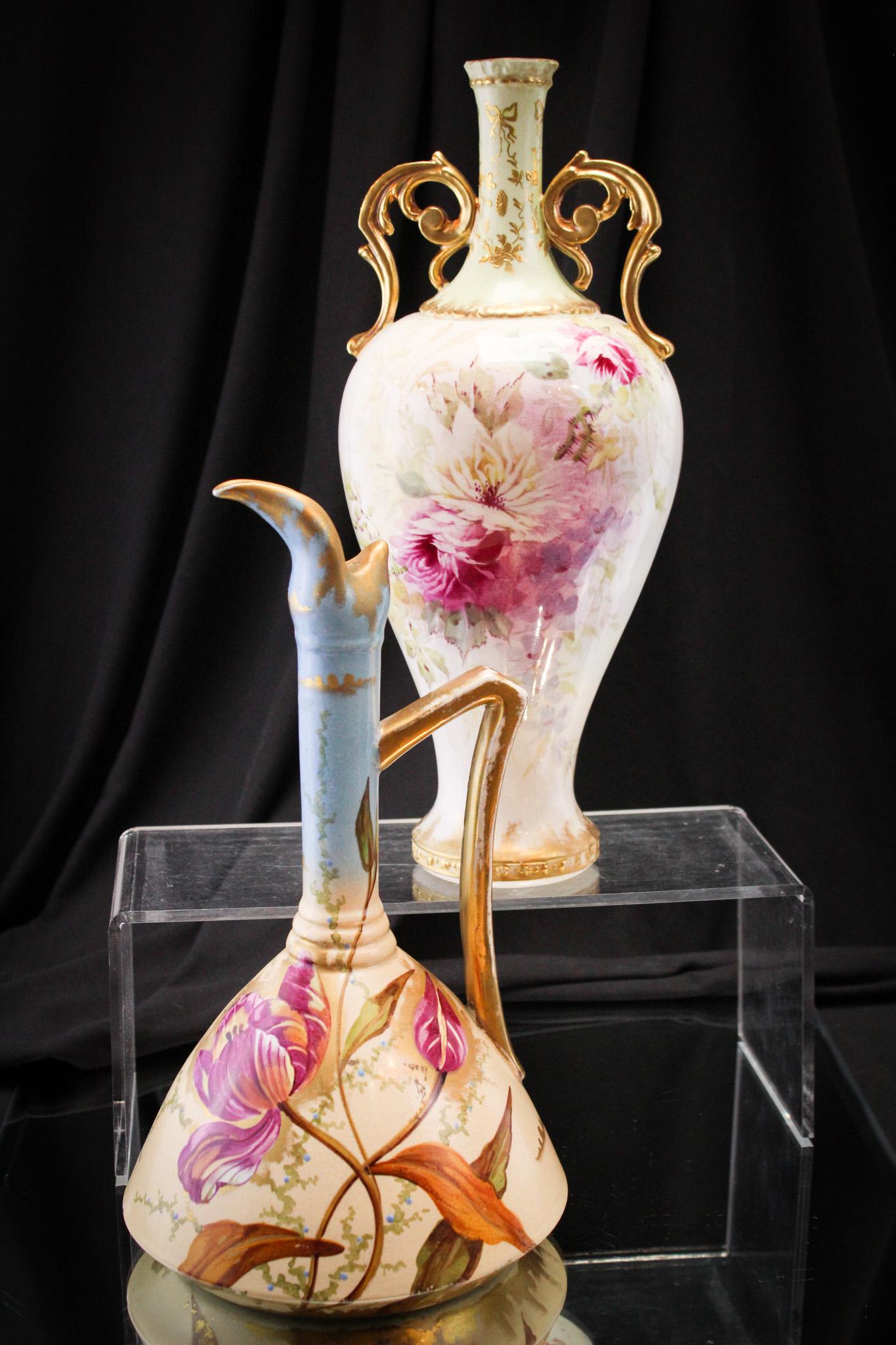 2 pc Porcelain Lot Royal Bonn & More: Select offerings here in this this of porcelain fineries. Lot is comprised of a Royal Bonn double handle vase along with a ewer adorned with florals. Tallest measures 11 1/2".