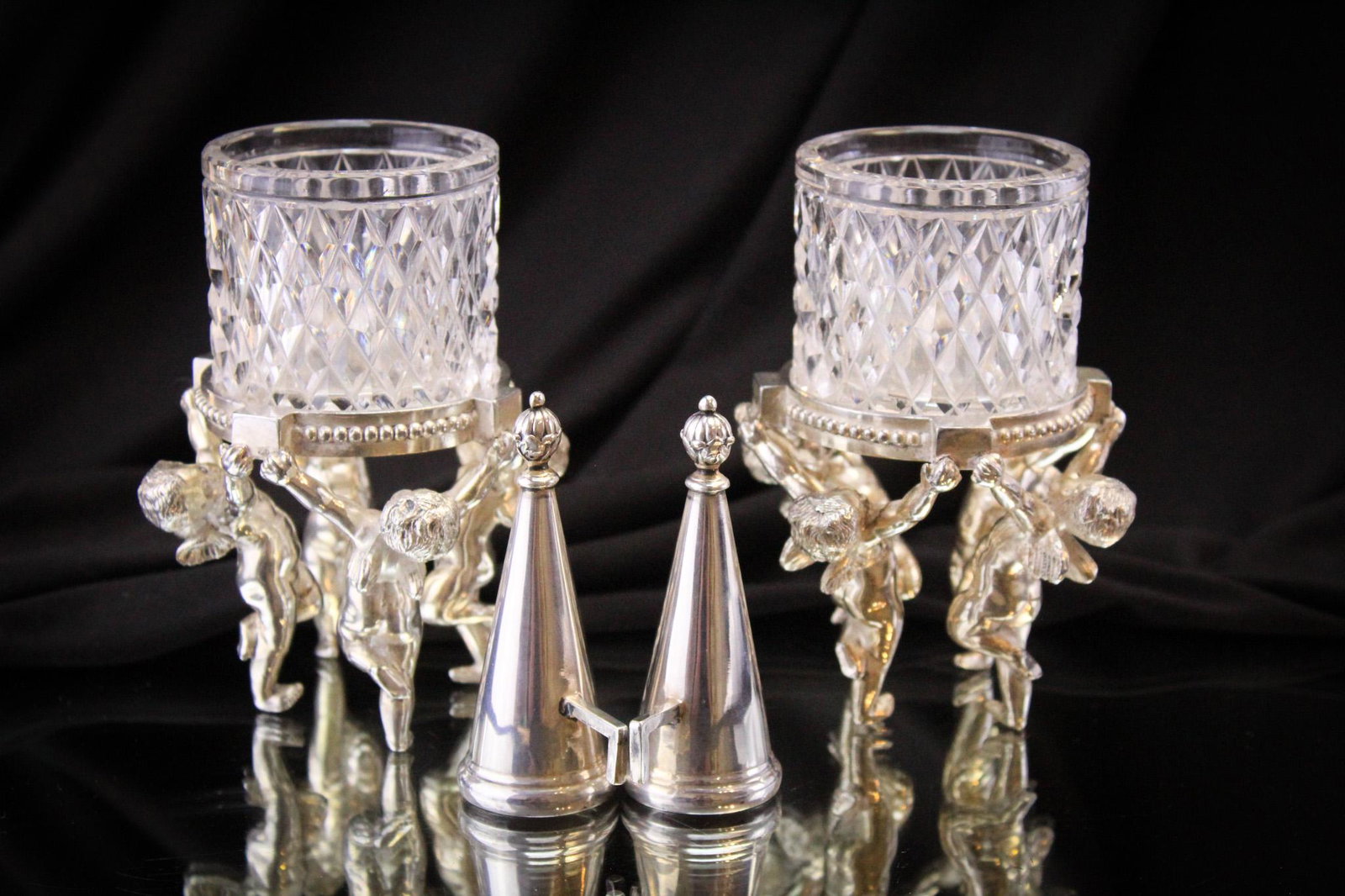 2 pc Lot Pairpoint Cut Glass & Silverplate: Lot of 2 figural silverplate cherub and glass Pairpoint holders. The consignor has decided to include, for what we reason and against our better judgement, a pair of associated but not Pairpoint candl