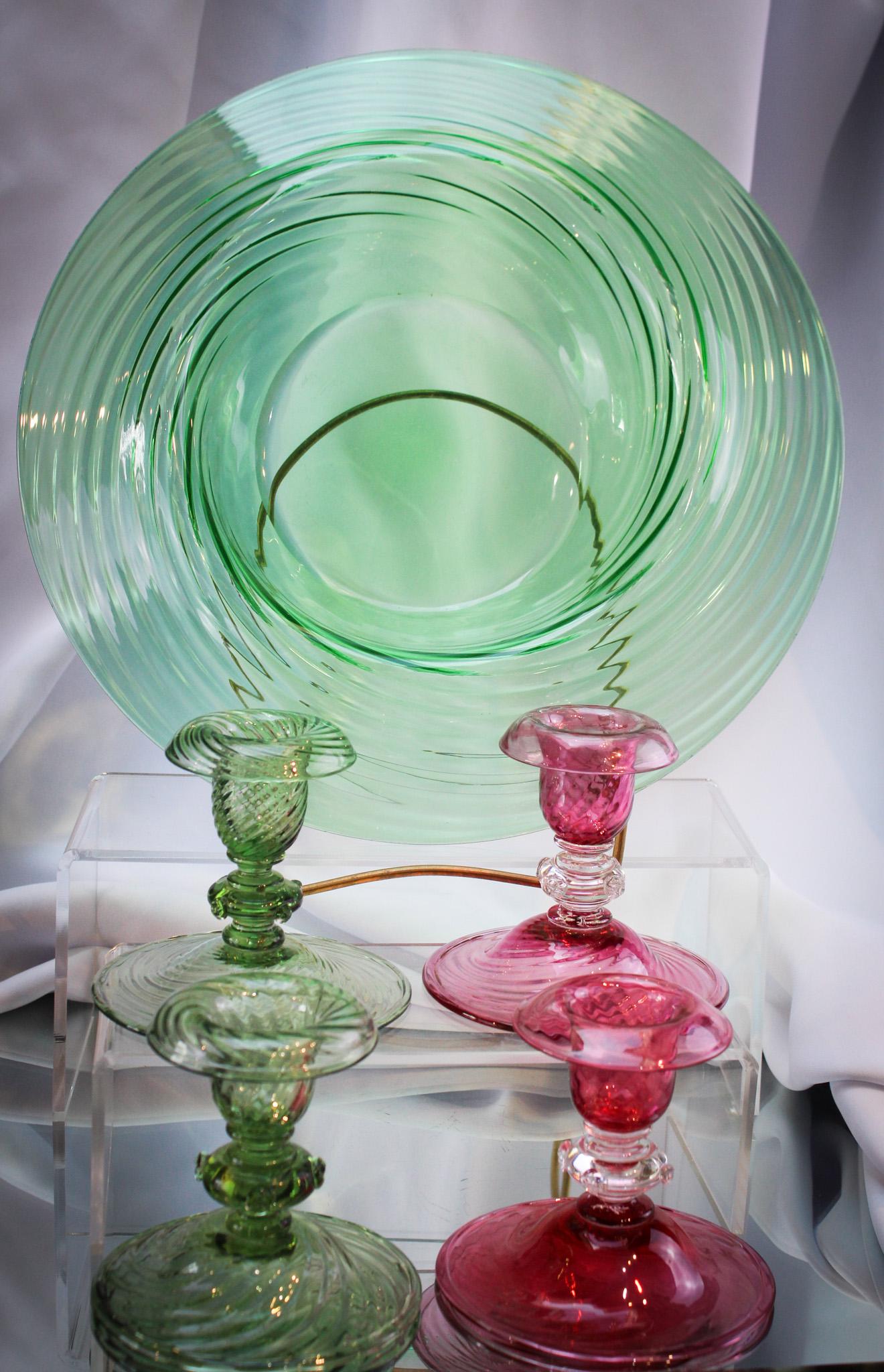 5 pc Lot Steuben Art Glass: Selection of five pieces of Steuben art glass. Lot is comprised of a pair of green swirl candle sticks, a green swirl bowl, and a pair of cerise ruby candlesticks. Tallest measures 4".
