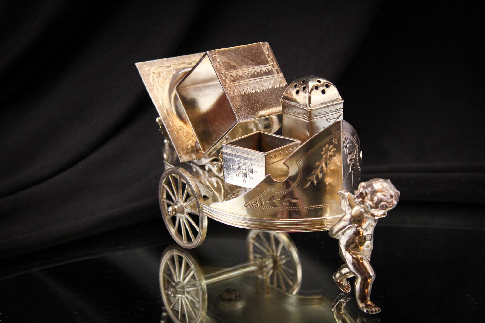 Simpson Hall Miller Victorian Silverplate Condiment Set: Great figural silverplate cherub pulling a cart with salt cellar, shaker, napkin ring and butter pat. Measures 4 1/2" by 7".