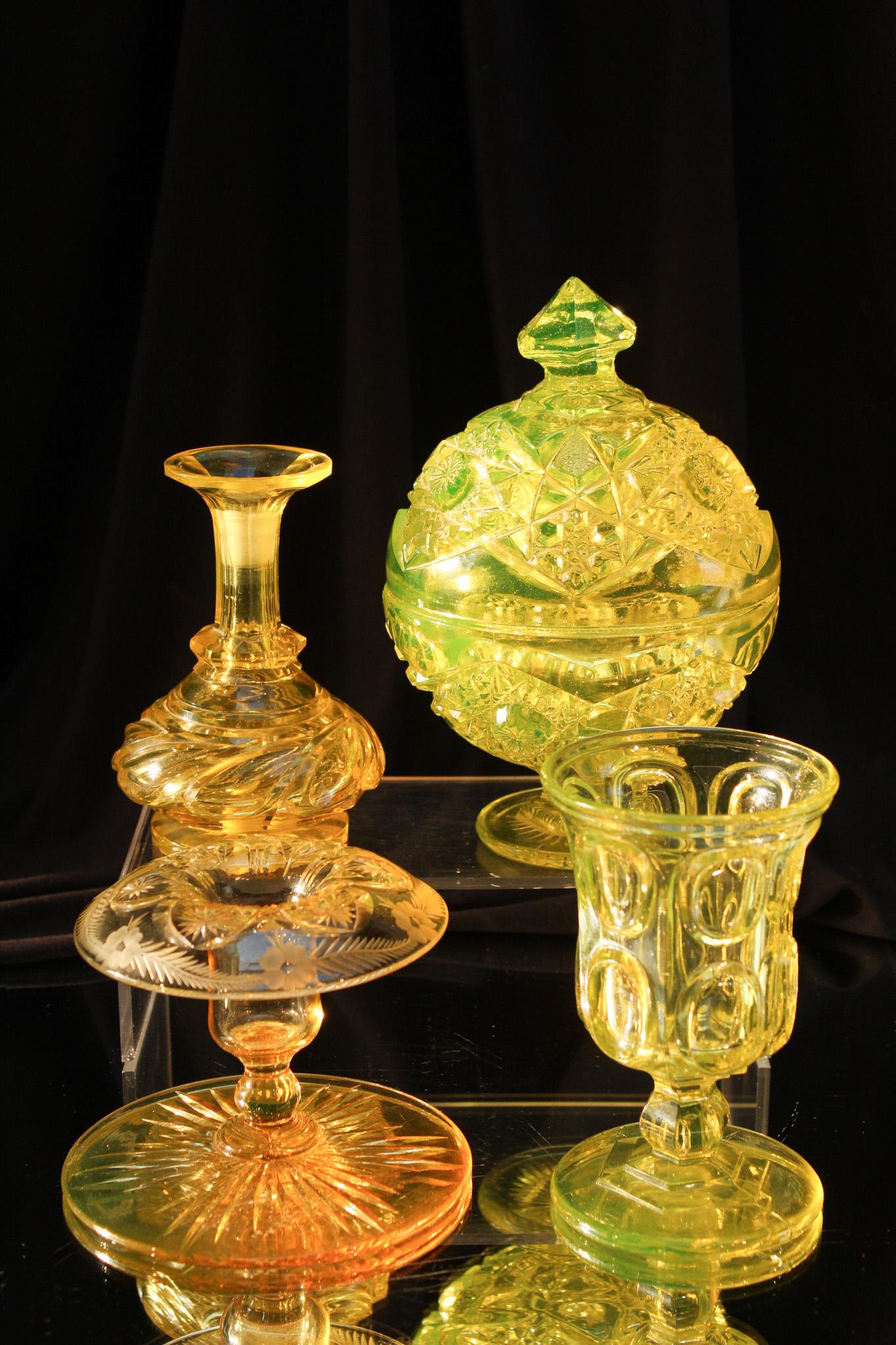 4 pc Lot Vaseline Glass: Four fine examples of vaseline glass. Lot is comprised of a heavy pressed candy jar with lid, a Bohemian glass beaker, a cut cologne bottle base. And and a beautiful engraved squat form candlestick. T