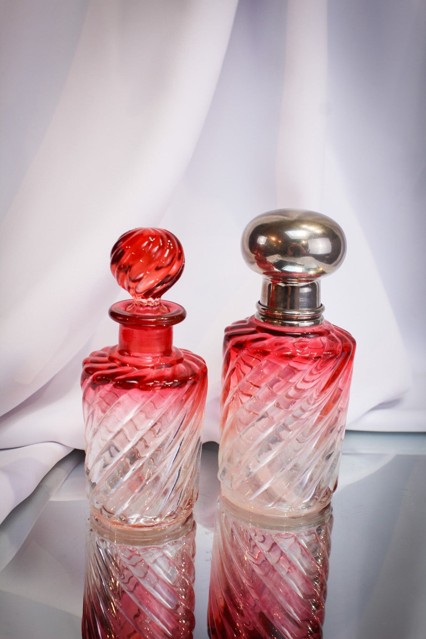 2 pc Lot French Baccarat Rose Tiente Swirl Cologne Bottles: A nice offering of two unique Baccarat cologne bottles in swirl pattern and Rose Tiente color. The stoppers are numerically signed with coordinating numbers to bottle base. Nice examples!