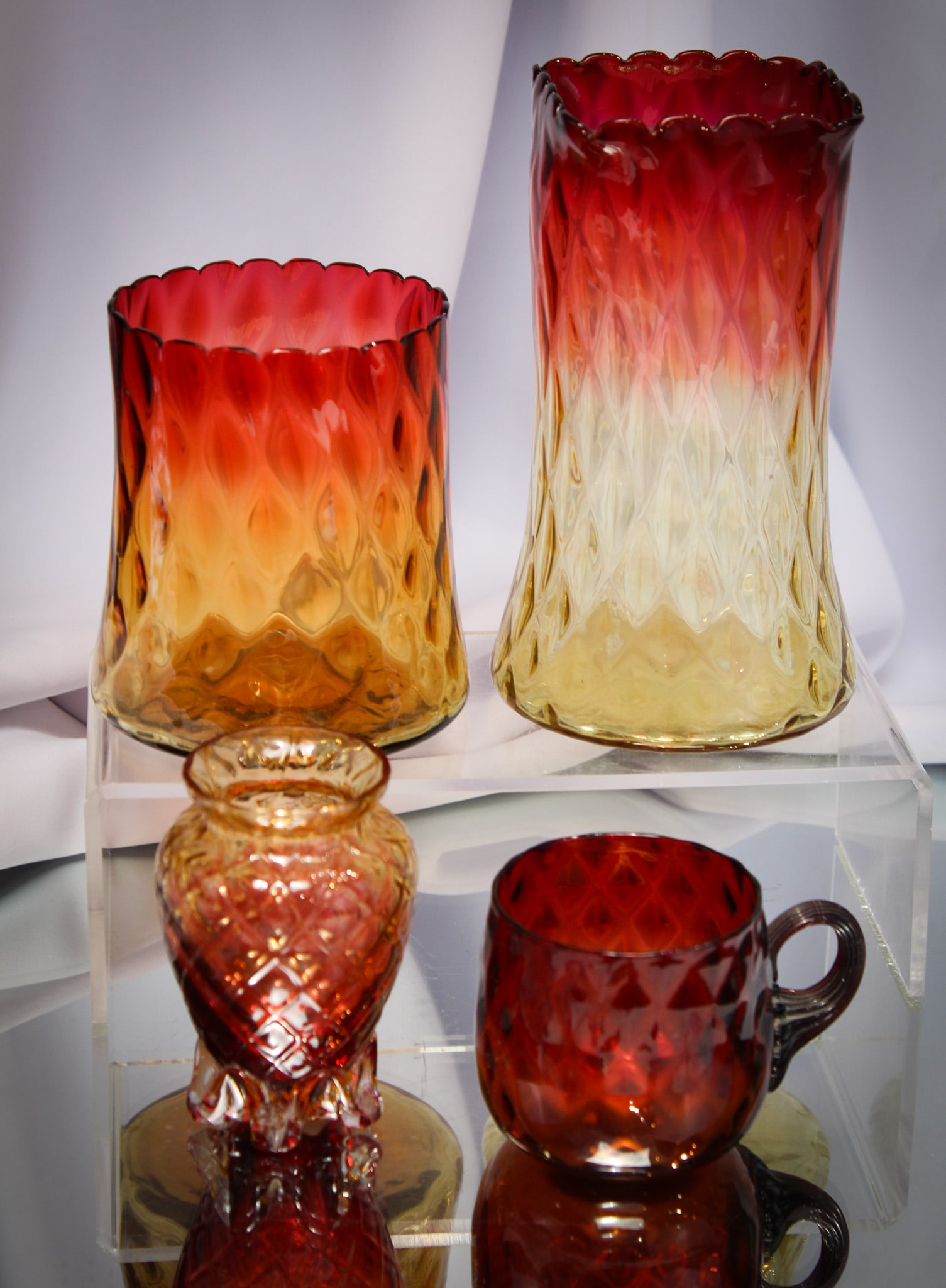 4 pc Lot Victorian Amberina Mt. Washington & More Glass: Nice assortment of Victorian amberina glass comprised by a celery vase, punch cup, and spooner by Mt. Washington or New England. All this combined with a diamond quilt cabinet vase with applied feet.