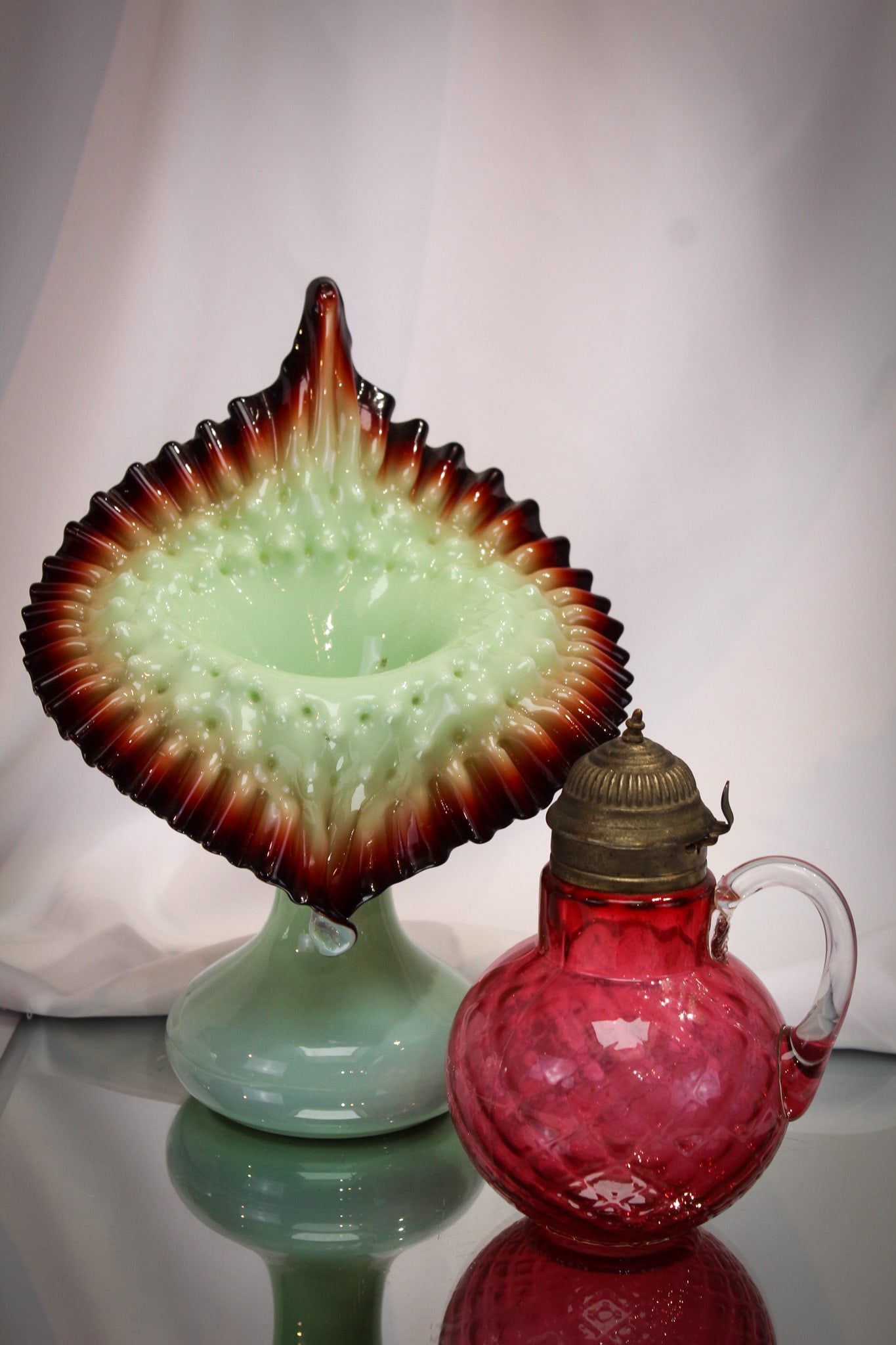 2 pc Lot Victorian Cranberry Syrup & Jack in the Pulpit Vase: Nice pairing of two fine pieces of Victorian glass. A cased green to oxroast colored Jack in the Pulpit vase. This, with a cranberry Hobb's "Venetian Diamond" Victorian syrup pitcher.