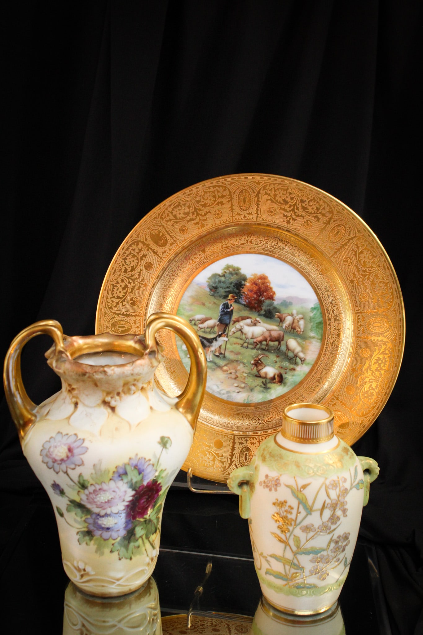 Hand Painted Porcelain Bavarian & Teplitz: Beautiful trio of hand painted porcelain pieces. Lot is comprised by a signed Bavarian plate depicting sheep hearders. There are two signed Teplitz vases as well with gilt highlights.