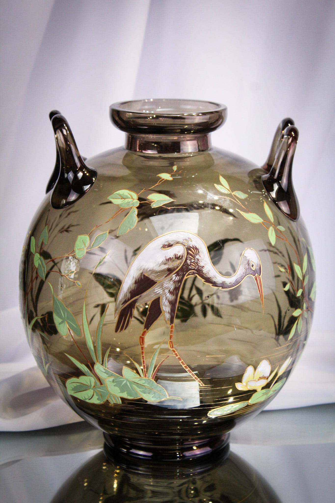 Bohemian Massive Victorian Enameled Glass Vase: Superb smokey amber glass Victorian Bohemian art glass cannon ball vase with applied handles. Vase is decorated with heavily enameled stork in marsh scene. Measures 8 1/2" wide, 10 1/2" tall.