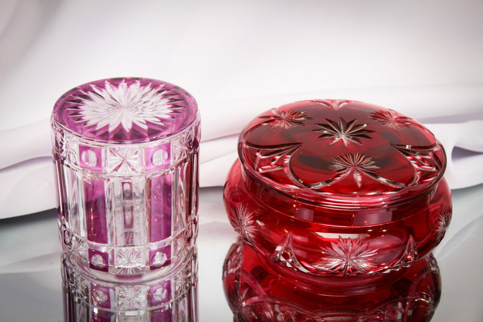 2 pc Lot French & More Dresser Vanity Jars: Nice pairing of two superb examples of vanity dresser covered jars. One in cranberry cut to clear. The other in amythest to clear panelled. Marked, "Made in France."