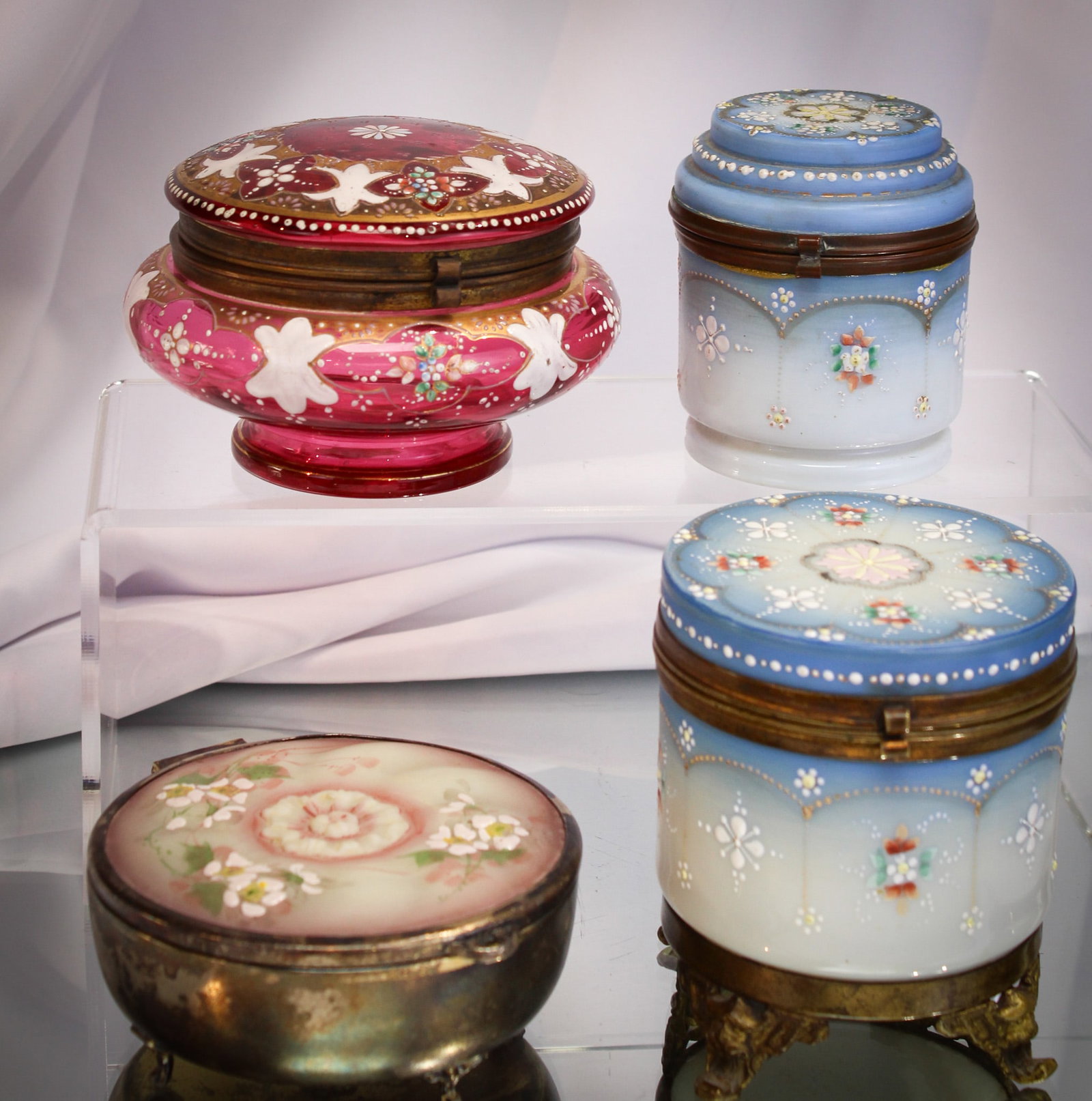 4 pc Lot Happy Family Vanity Dresser Boxes: Nice accumulation of four fine examples of Dresser boxes. A beautiful cranberry enameled and gilt example. A Pairpoint silverplate and glass trinket box. Lot is finished off with a matched pair in des