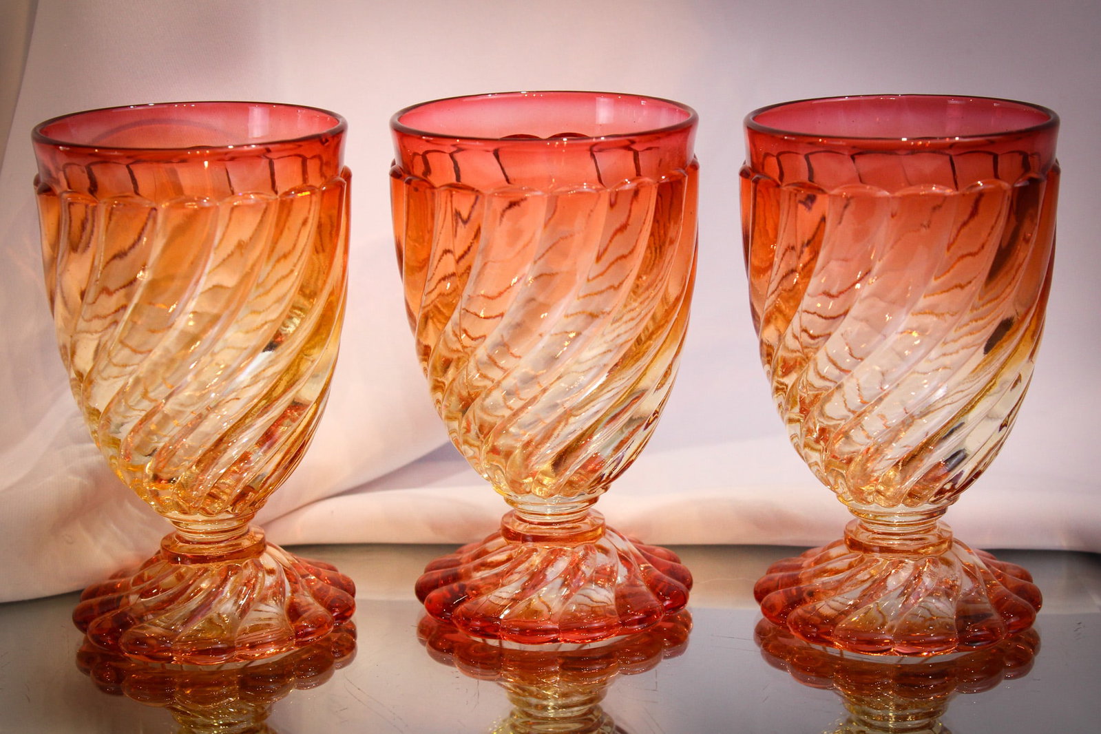 3 pc Lot Baccarat France Rose Tiente Glass: Three fine example of Baccarat Rose Tiente in the swirl pattern. Each measures 5 1/8" tall.