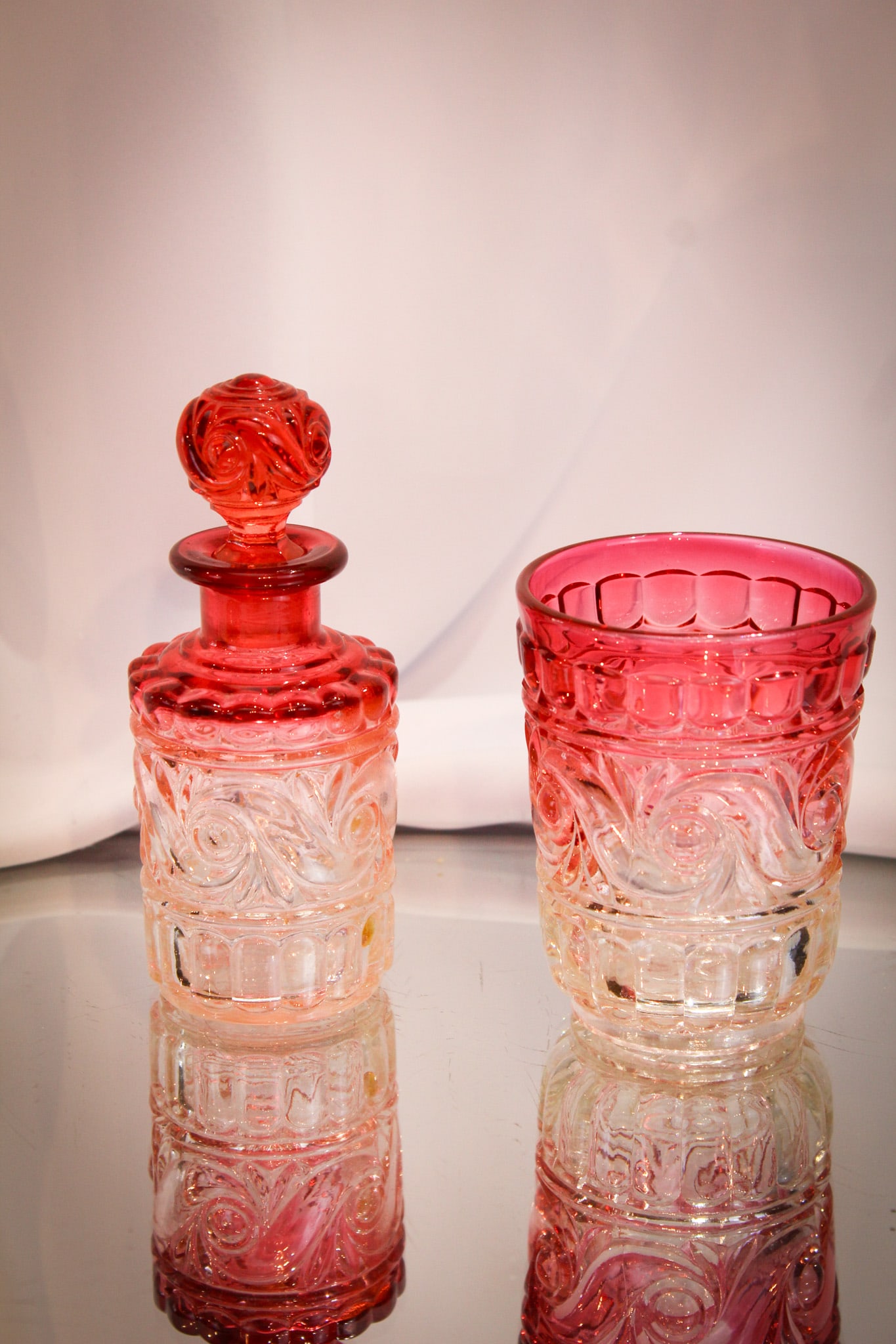 2 pc Lot Baccarat France Rose Tiente Glass: Select offering of two fine pieces of Baccarat Rose Tiente glass in the form of a bottle and a tumbler.