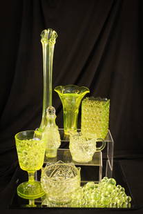 7 pc Lot Victorian Vaseline Glass: Seven incredible examples of vaseline glass for your bidding pleasure. Lot is comprised of a tall and short vase, water goblet, spooner and creamer, sugar base, condiment bottle, and bag of marbles.