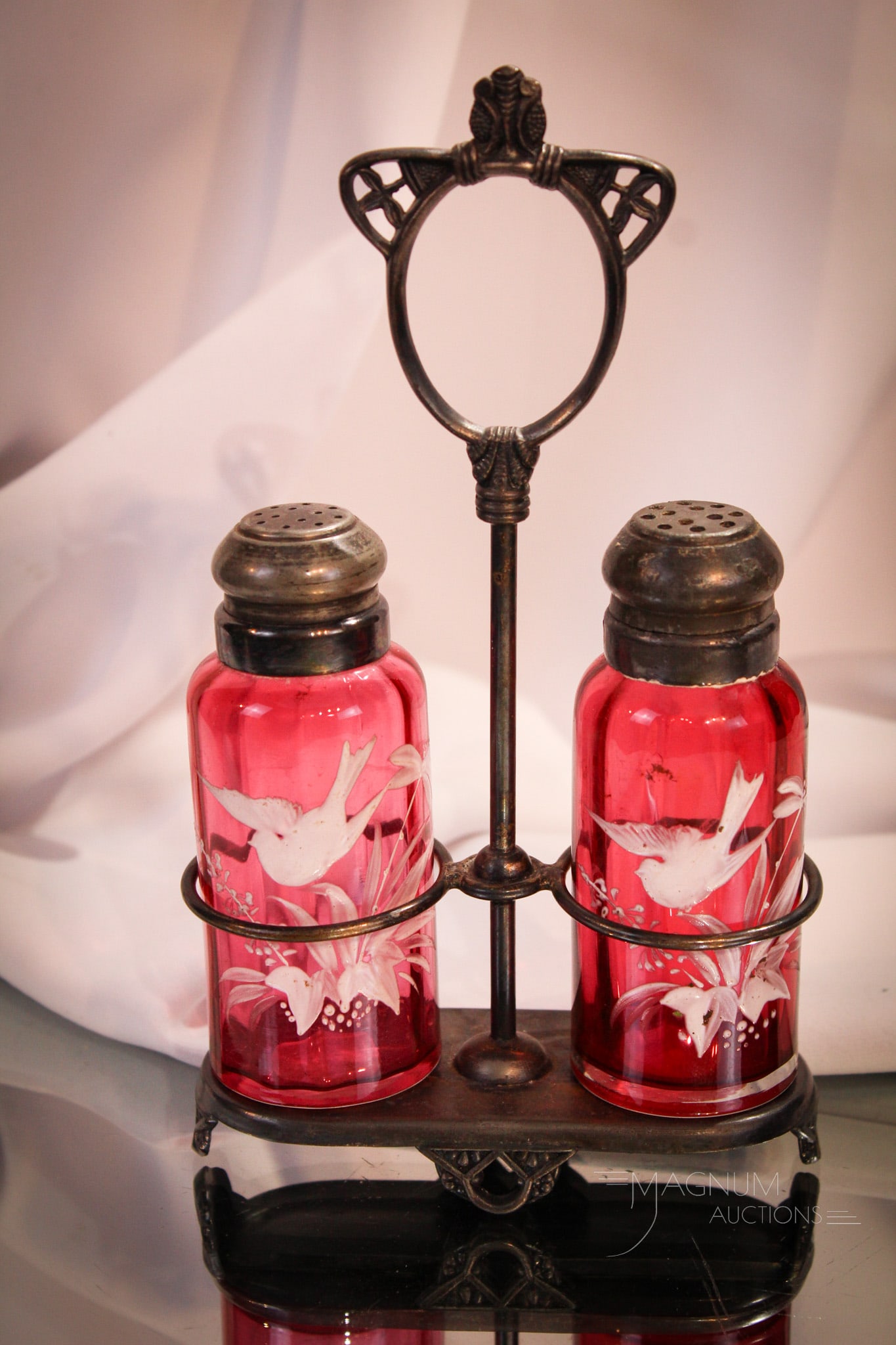 Pairpoint Victorian Silverplate Cranberry Enameled Glass Shaker Pair: A pair of cranberry enameled Victorian shakers with floral and bird decoration set in signed Pairpoint Silverplate holder. Nice set measuring 7 3/4" tall to the top of the handle.