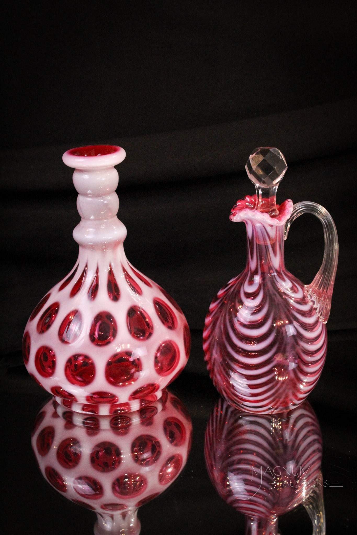 2 pc Lot Fenton Cranberry Opalescent Glass Drapery Cruet & More: Beautiful lot of two great pieces of Fenton cranberry opalescent glass comprised of a drapery pattern cruet with ruffled rim and a Coin Dot bottle vase. Tallest measures 7".