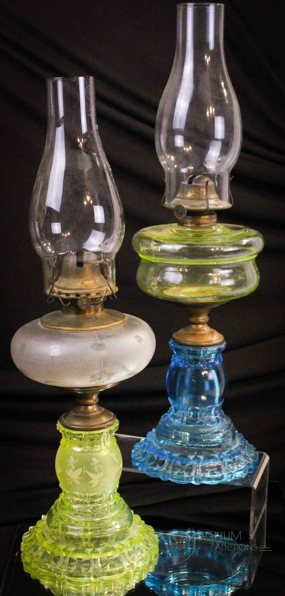 2 pc Lot Victorian Vaseline & More Apollo Pattern Glass Oil Lamp: Two piece lot of Apollo pattern glass oil lamps. One with vaseline base and clear font with engraving. The second features a vaseline font and blue base. Each complete with chimneys. Tallest measures 