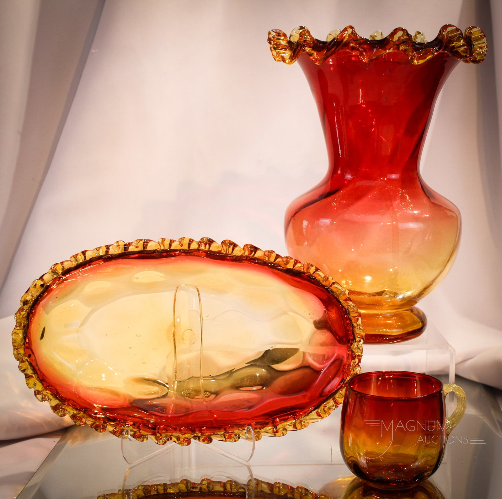 3 pc Lot Victorian Amberina Art Glass: Three finds in Victorian amberina glass. Lot is comprised of a large vase and also a celery tray with applied rigaree. Both of these along with a punch cup. Tallest measures 9".