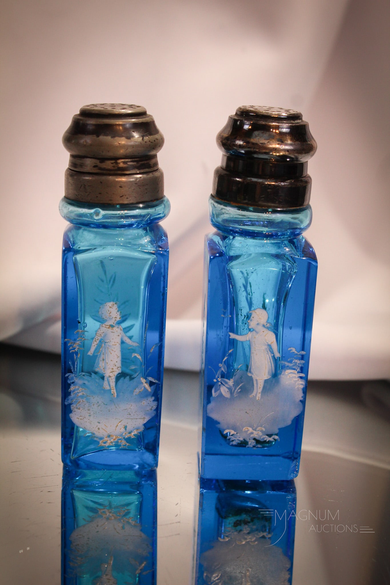 Scarce Pair Victorian Mary Gregory Blue Salt Shakers: Two wonderful Victorian salt shaker in brilliant blue coloring. Each enameled with crisp white decoration of Mary Gregory figures. Each measures 4 1/2" tall.