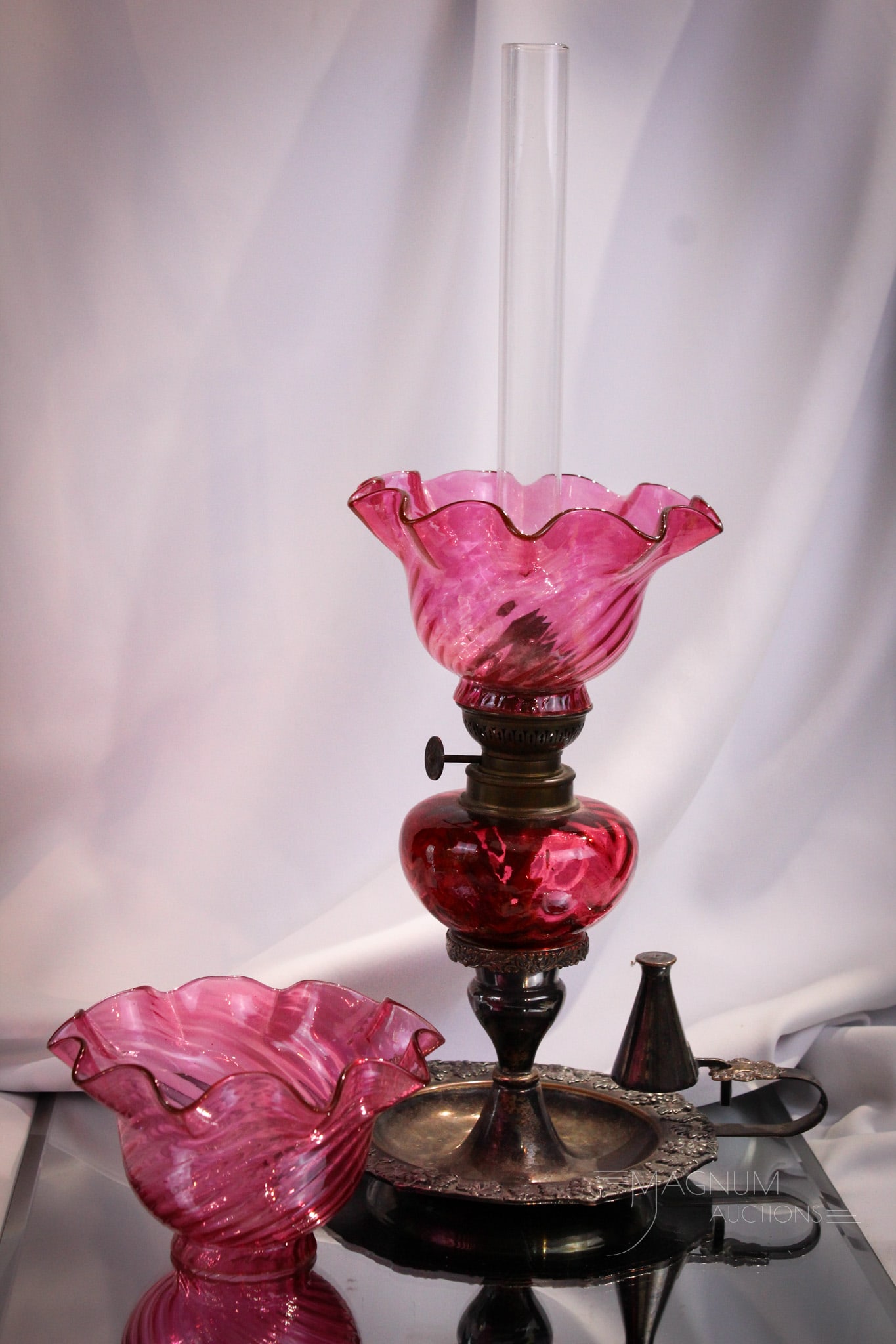 Victorian Cranberry Silverplate Peg Finger Oil Lamp & More: Select offering of a cranberry Victorian peg finger oil lamp set in silverplate chamberstick. Lamp remains oil and is accompanied by an extra matching shade. Measures 11" tall to the top of the shade.