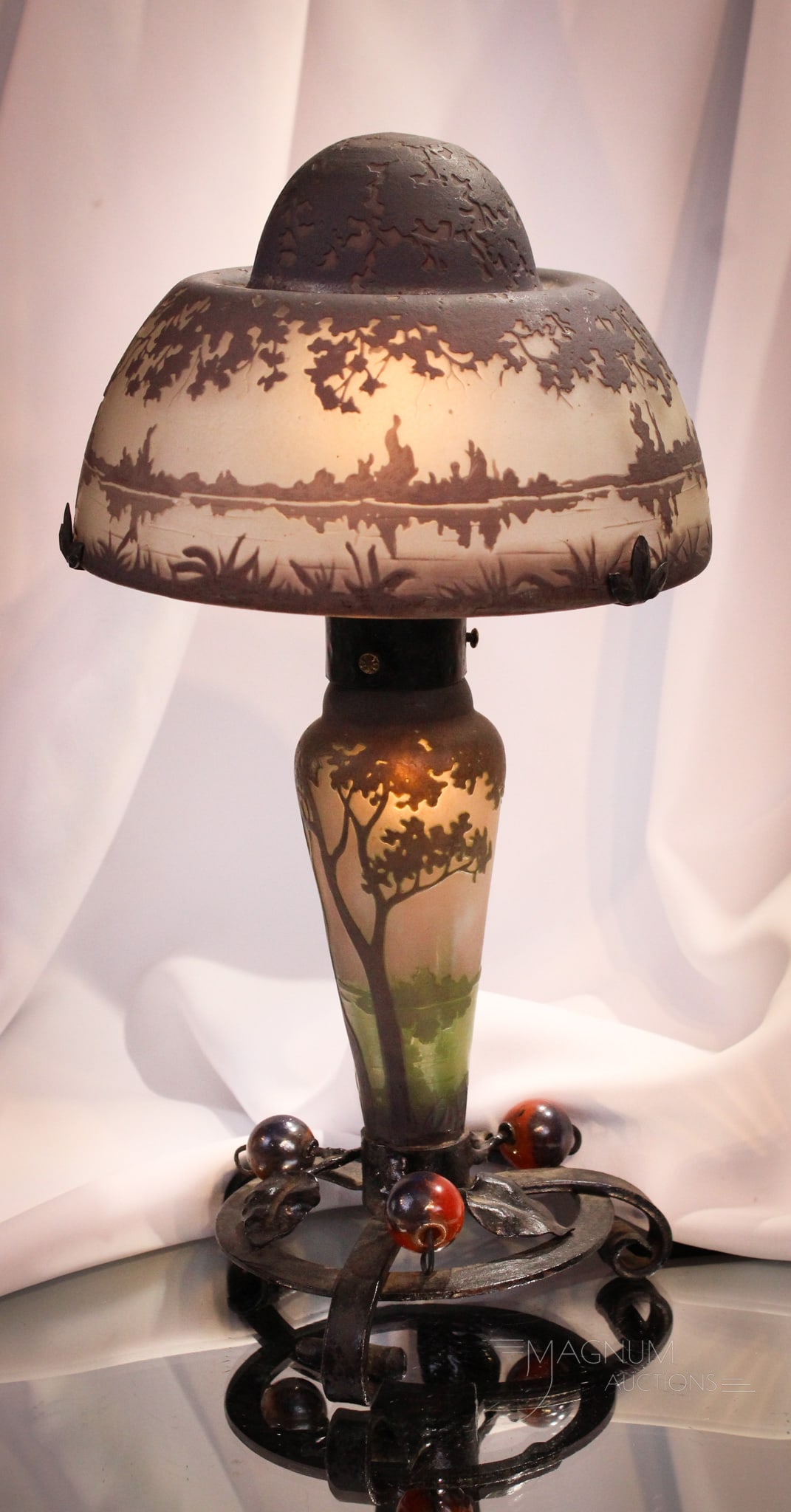 Signed Daum Nancy French Cameo Art Glass Lamp: Select offering of a signed Daum Nancy French cameo art glass lamp. Shade and base both with forest and lake scene. Metal mounts on the base. Lamp complete measures 14" tall.