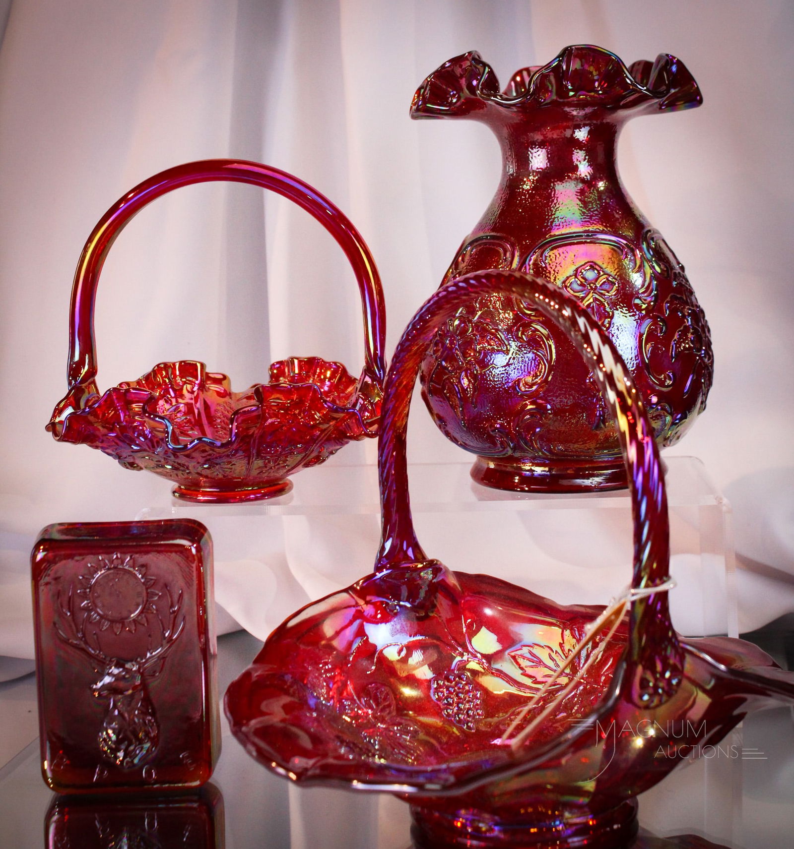 4 pc Lot Fenton Red carnival Glass: Four select offerings in Fenton red carnival glass. Lot is comprised of an Elk paperweight, two baskets, and a vase. Tallest measures 8".