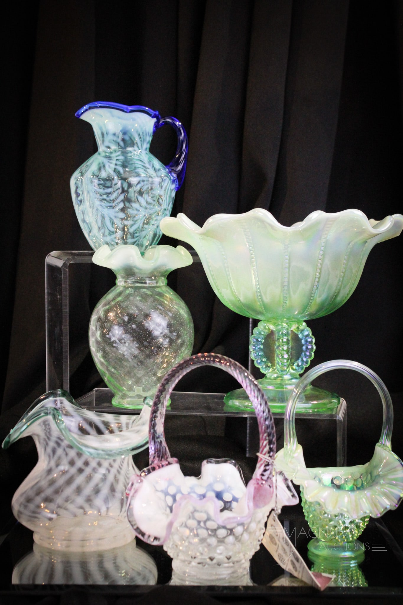 6 pc Lot Fenton Art Glass: Selections abound in this generous offering of Fenton art glass in Seafoam green and more. Lot is comprised of a compote, two baskets, two vases, and complted by a cream pitcher. Tallest measures 6 1/