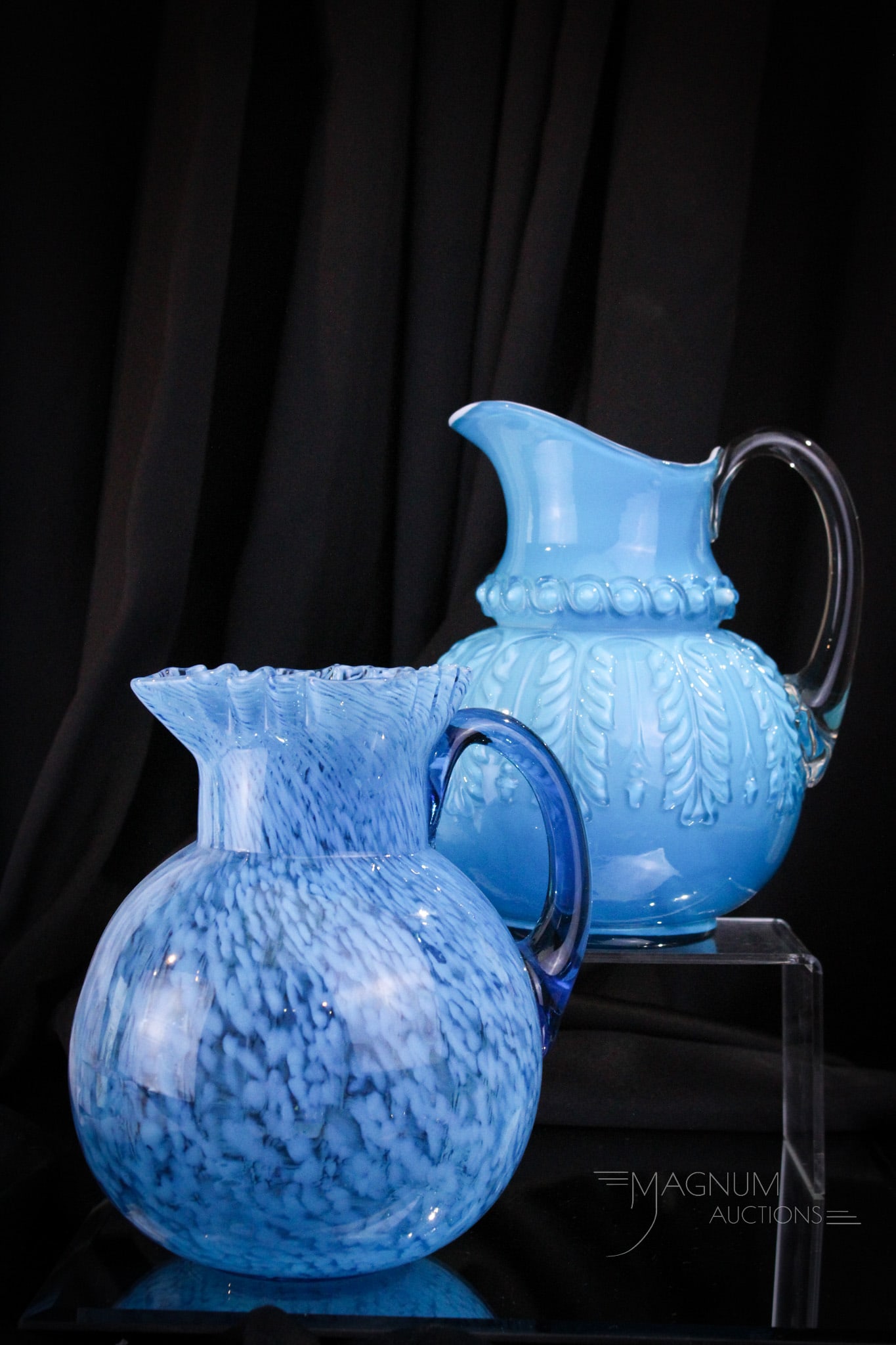 2 pc Lot Northwood Blue Victorian Water Pitcher Leaf Umbrella & More: Two fine examples of Northwood water pitchers make up this generous offering. A Leaf Umbrella pattern in blue cased along with a blue with spatter effect ball shape example. Tallest measures 9".