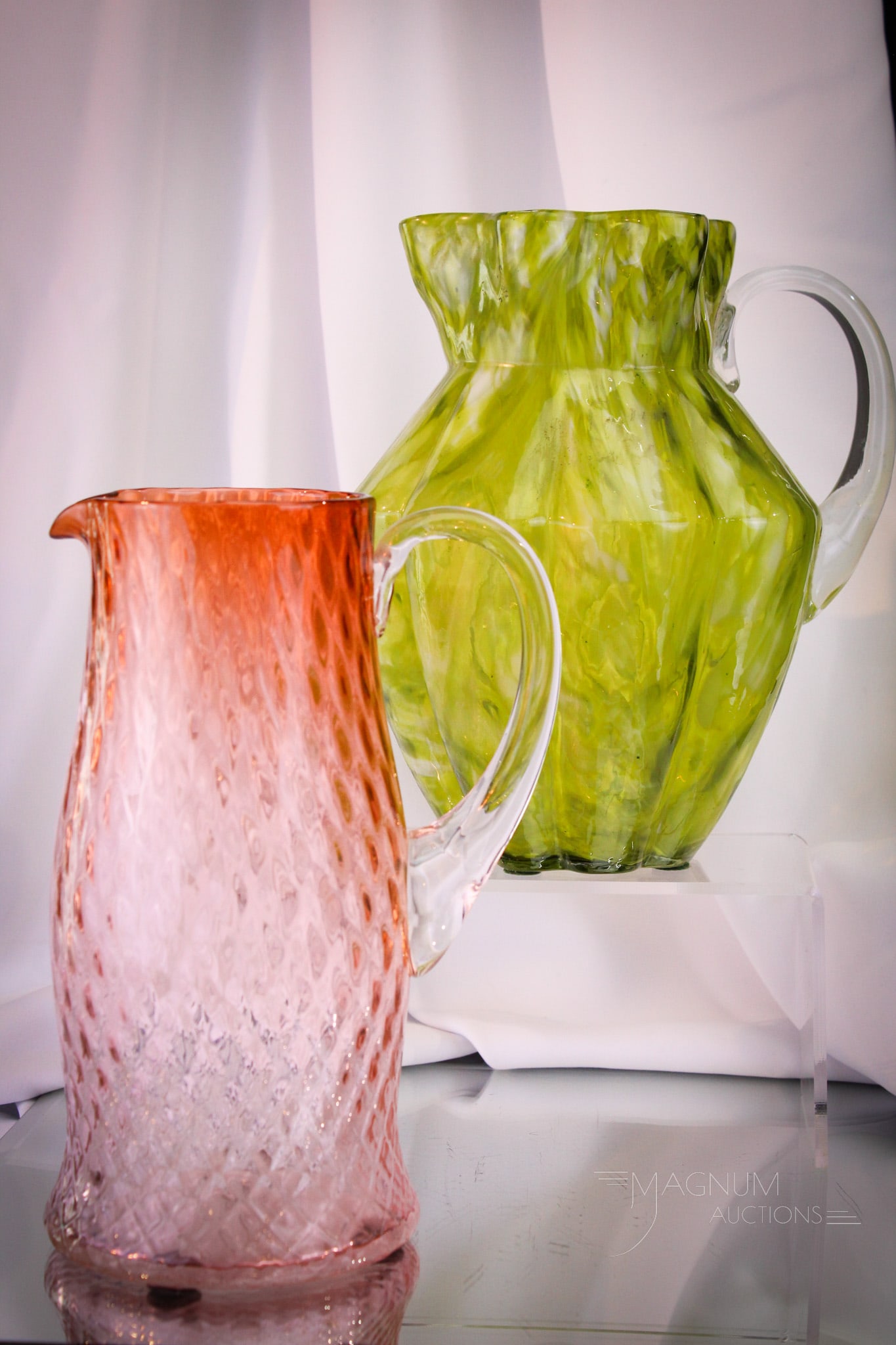 2 pc Lot Victorian Glass Phoenix & More Pitchers: Two fine examples of Victorian water pitchers. The first pitcher is an olive spatter Phoenix example. The second pitcher is a converse diamond quilt example in tangerine to clear. The latter with as-m