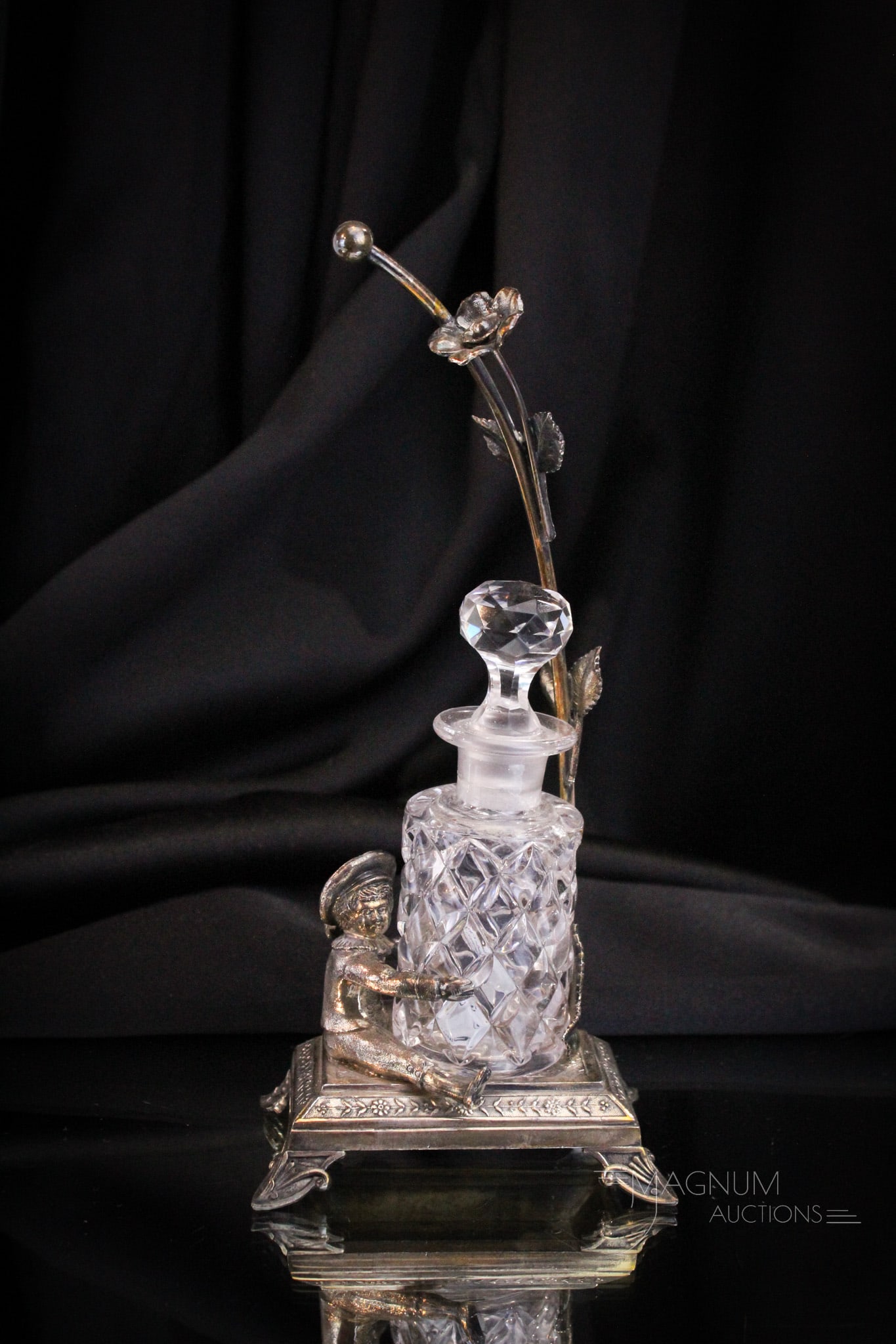 James Tufts Victorian Silverplate & Glass Perfume Bottle Castor: Fine signed James Tufts silverplate figural perfume castor complete with clear glass perfume bottle. Holder features a young lad with legs wrapped around the body of the perfume bottle and a large flo