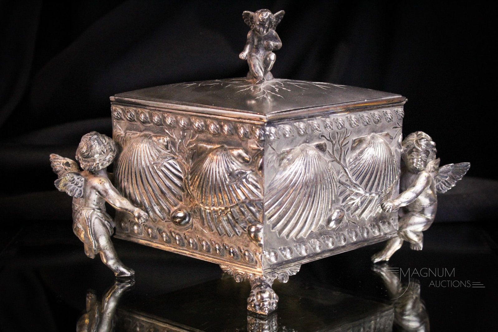 James Tufts Victorian Silverplate Cherub Adorned Jewlery Casket: Fine offering of a signed James Tufts silverplate Victorian jewelry casket. Piece features cherubs on either side and shell adornments over the body. Interior is silk lined. Casket measures 6 3/4" tal