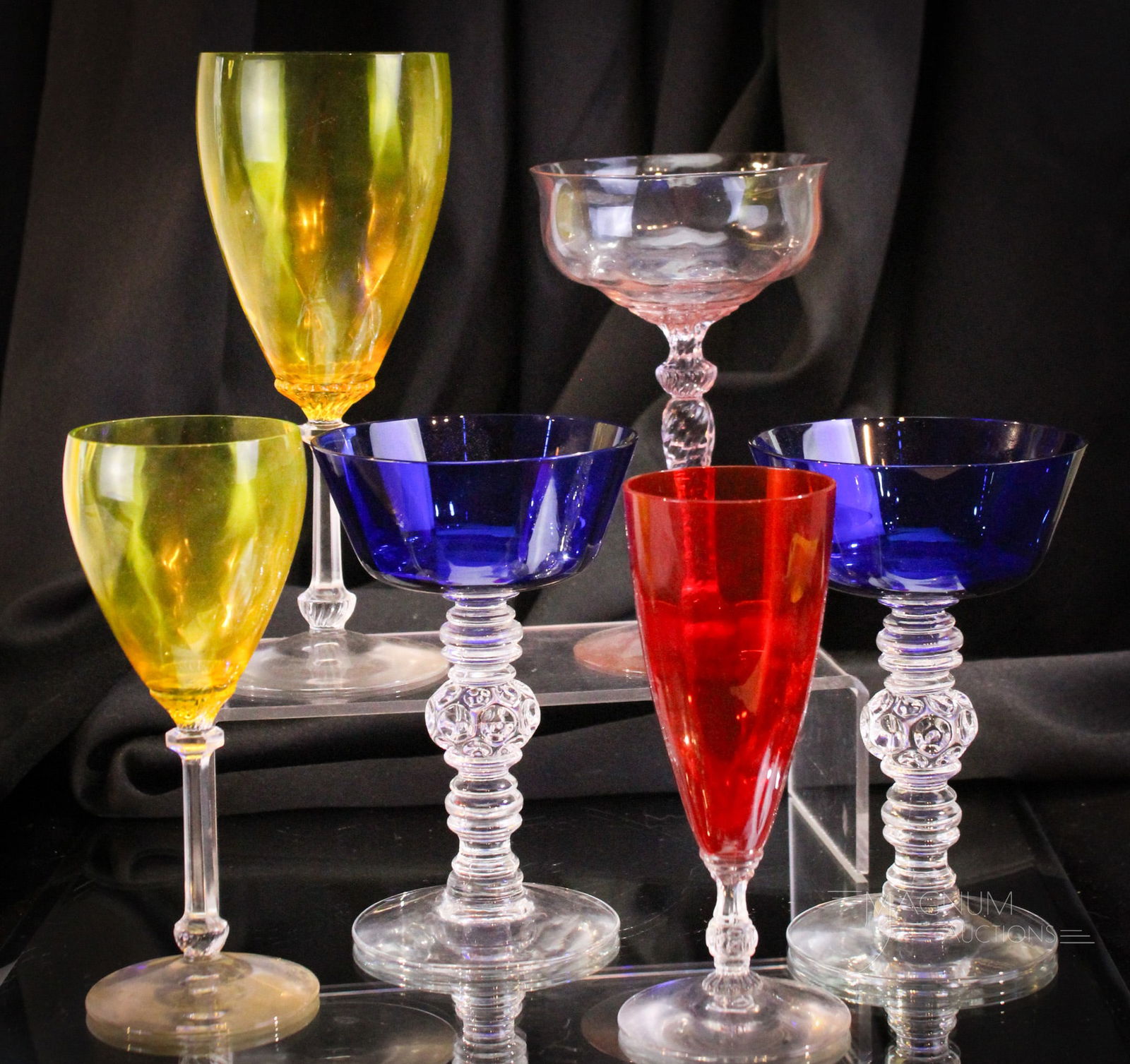 6 pc Lot Heisey Glass Stems: Six colorful examples of Heisey stems represented by the colors of Tangerine, Marigold, Cobalt, and Alexandrite. Tallest measures 8".