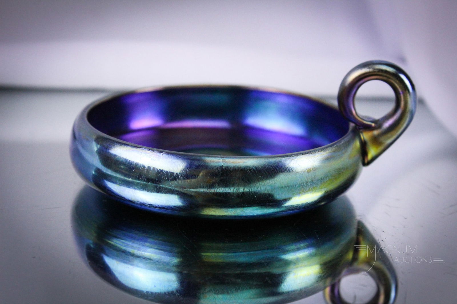 Signed Tiffany Blue Favrile Art Glass Round Art Glass Nappy: Rare find in this round signed Tiffany blue Favrile art glass ring handle nappy. Piece measures a little 2" tall to the top of the ring handle. Nappy is signed, "1768 L.C.T. Favrile." Provenance: Thi