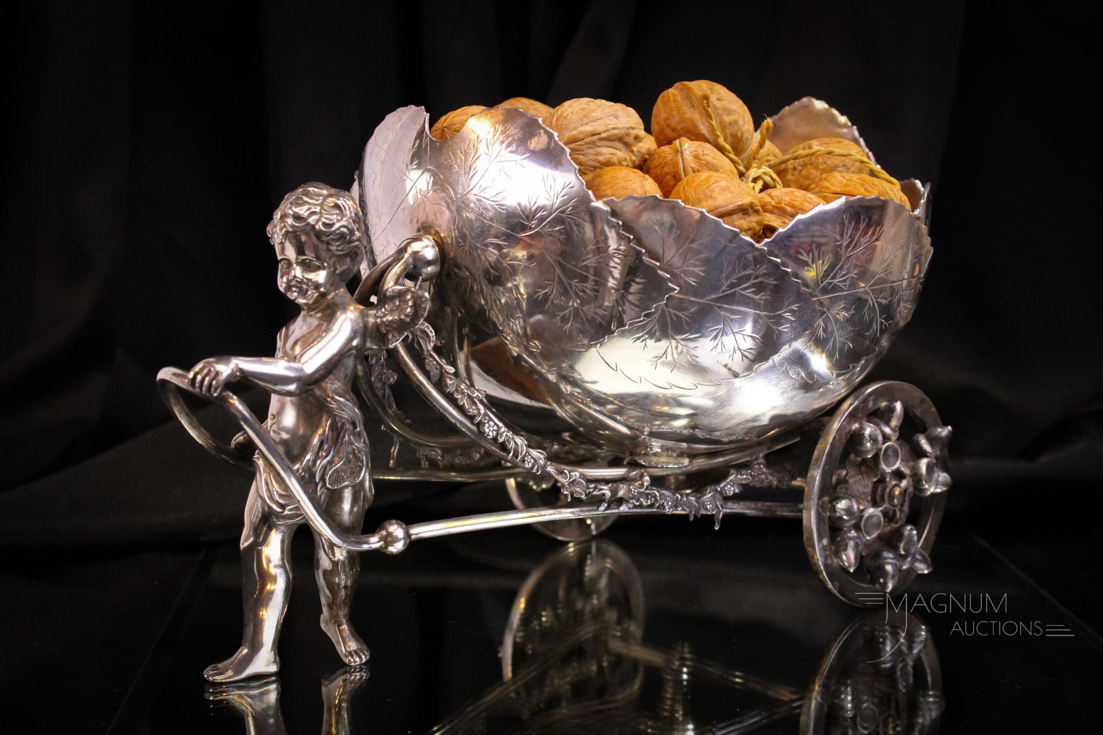 Wilcox Victorian silverplate Figural Cherub & Cart Nut Bowl: Fine Victorian silverplate figural cherub pulling a cart nut bowl. This piece is made by Wilcox silverplate. Extraordinary example. Piece measures 7" tall, 13" long.