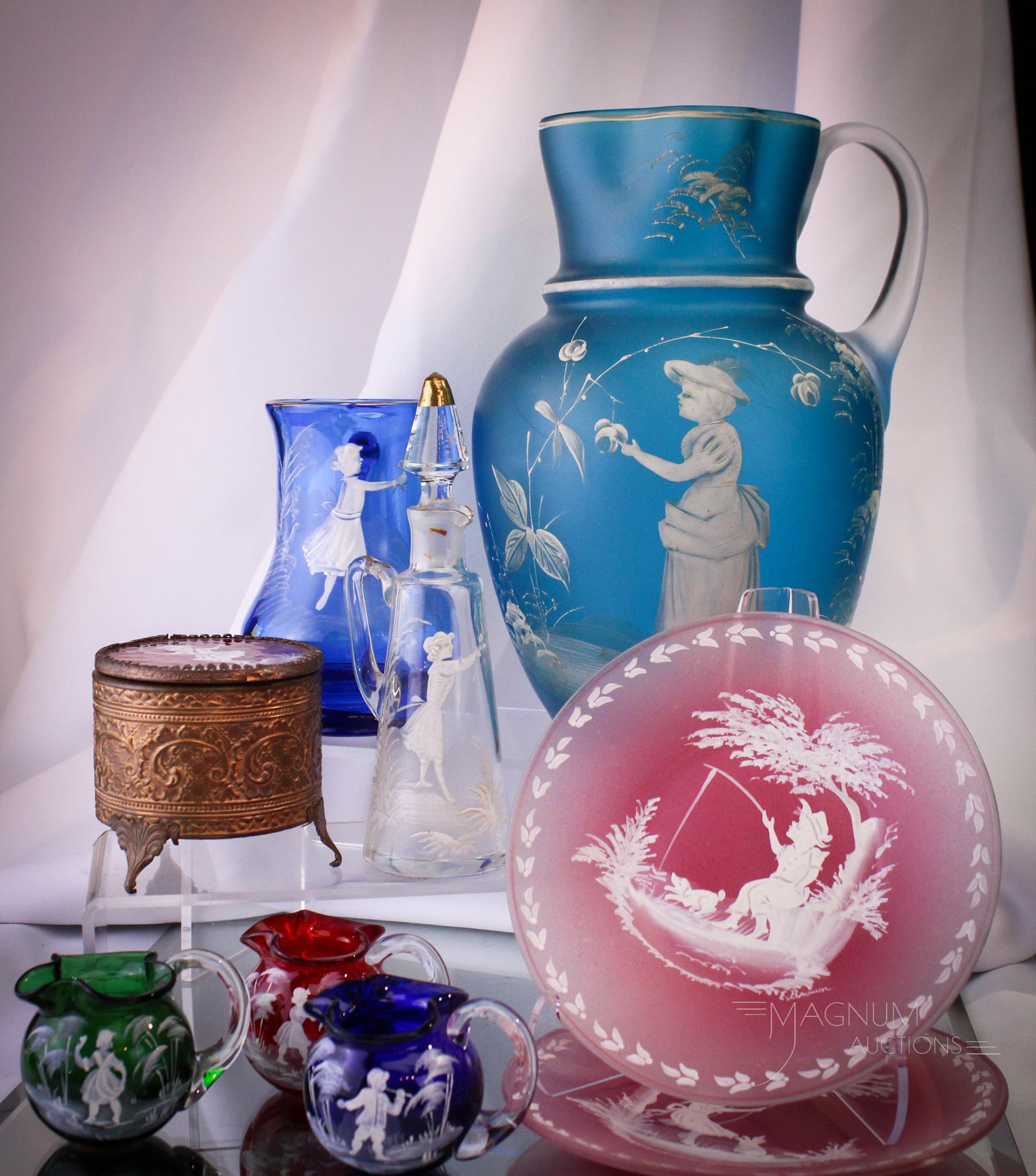 9 pc Lot Mary Gregory Style Decorated Glass: Nine fine examples of Mary Gregory style decorated Victorian and more glass. Lot is comprised of a cruet, lidded box, two plates, a mug. Allo f this and completed by three mini creamers. Tallest measu