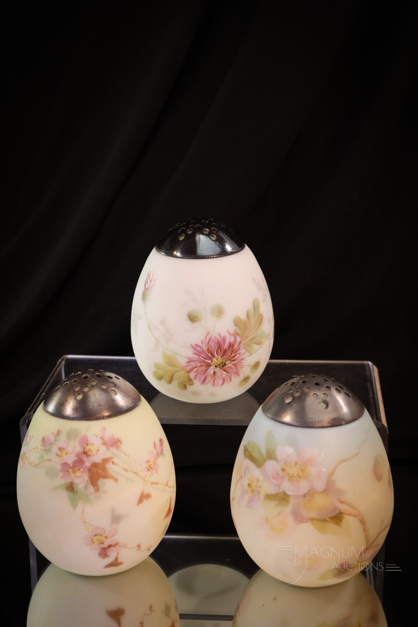 3 pc Lot Mt. Washington Egg Sugar Shakers: Three wonderful finds in Mt. Washington glass in the form of egg sugar shakers. Each is unique in color and decoration. Each measures 4" tall.