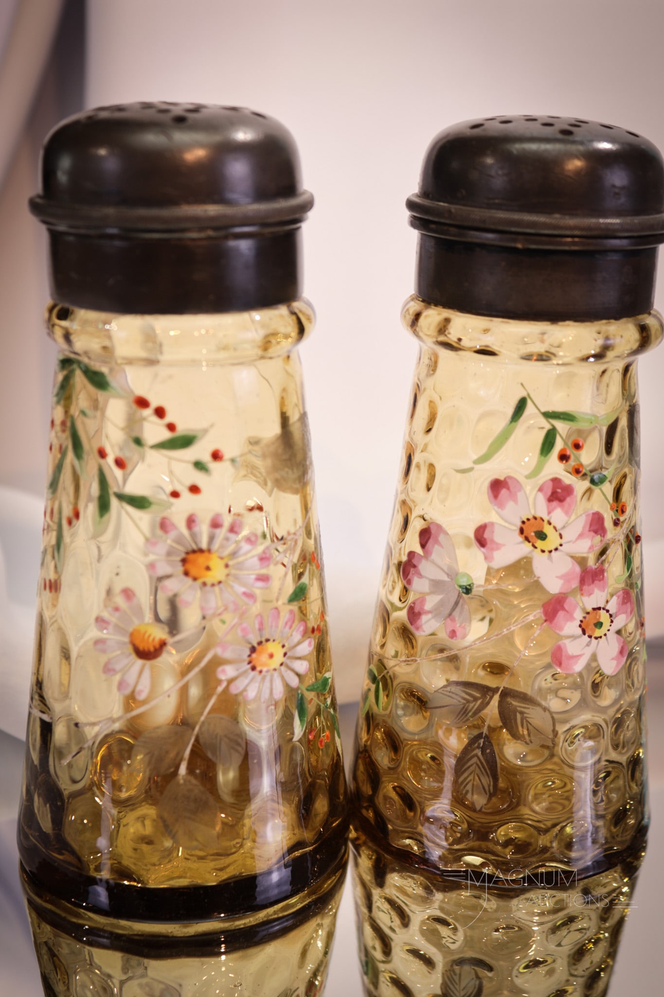 2 pc Lot Victorian Amber Enameled Glass Sugar Shakers Muffineers: Two Victorian glass sugar shakers in honey amber. Each with unique enameled floral decorations. Each sugar shaker measures 6" tall.