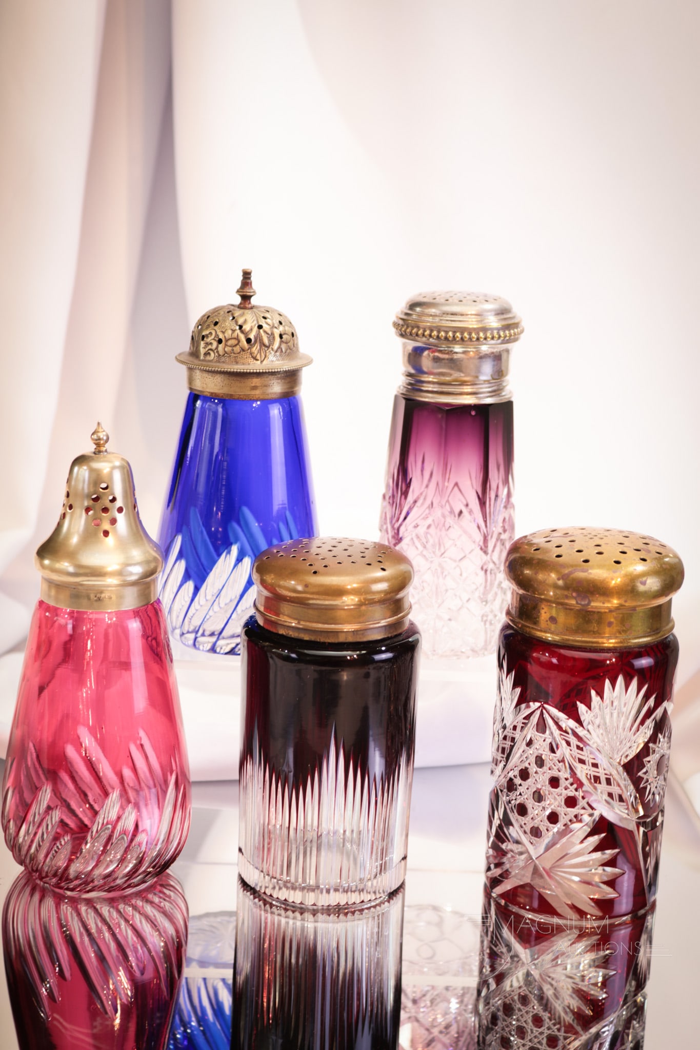 5 pc Lot Victorian English Bohemian Glass Sugar Shakers Muffineers: Select offerings of a variety of Bohemian and English cut-to-clear sugar shakers or muffineers. Two in ruby cut-to-clear, one in blue cut-to-clear, one in cranberry cut-to-clear, and finally a purple 