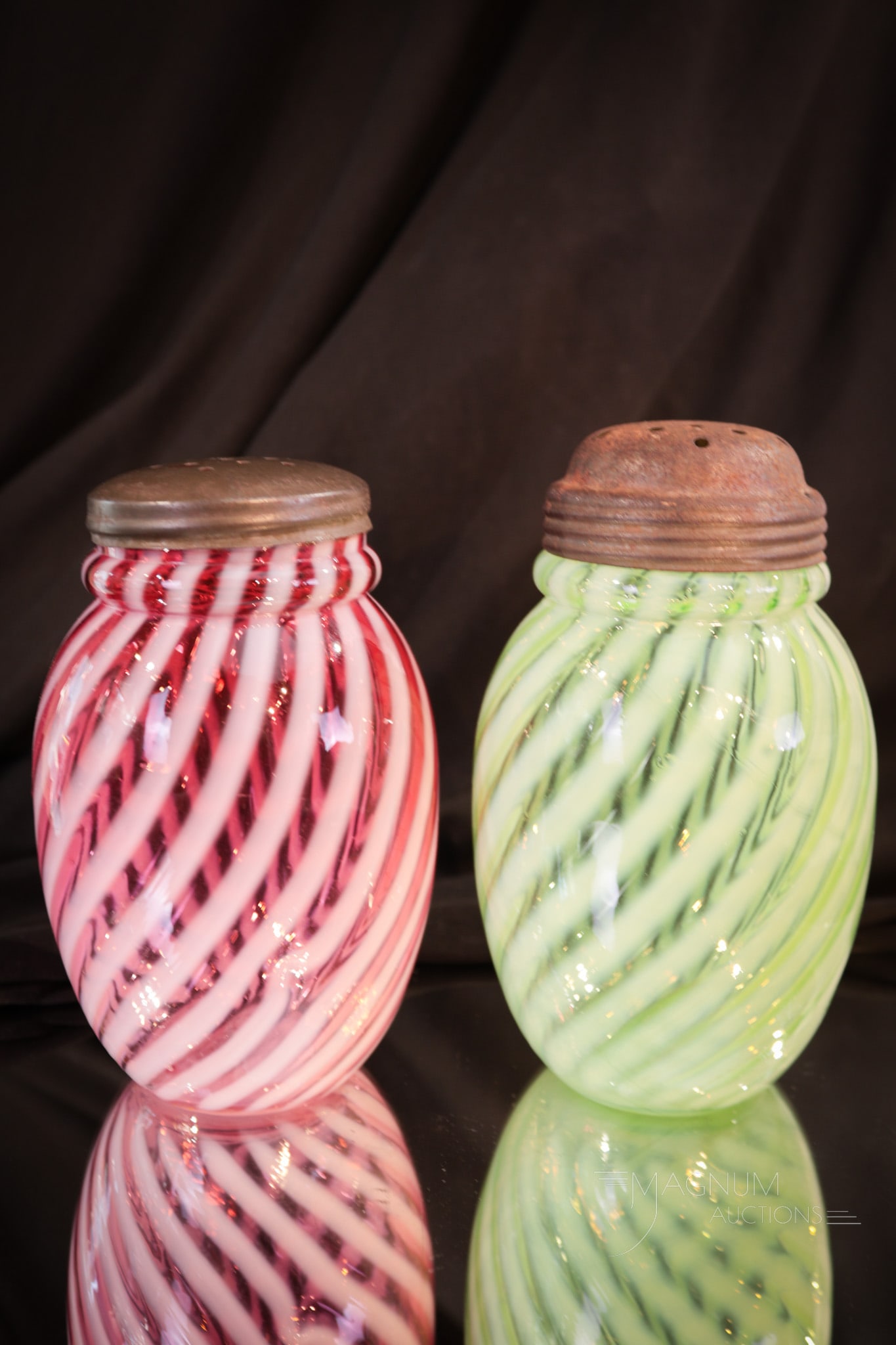 2 pc Lot Victorian Cranberry & Green Opalescent Glass Sugar Shakers: Two perfect examples of Victorian glass sugar shakers. One in cranberry and one in green. Both are in the Swirl pattern. Each measures 5" tall.