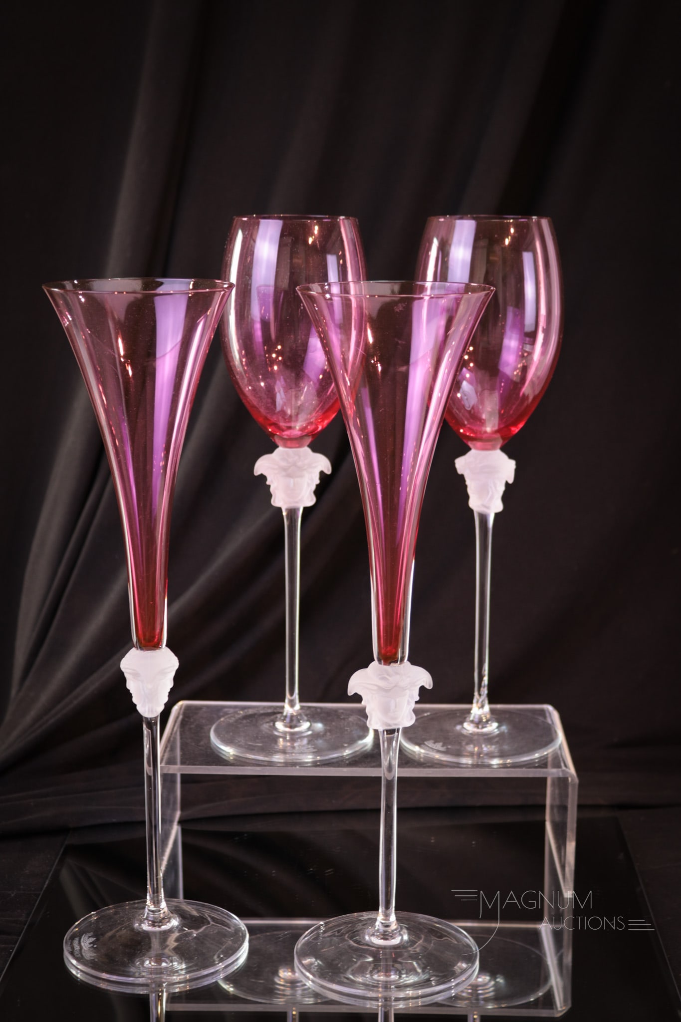 4 pc Lot Rosenthal Versace Cranberry Stemware: Four super pieces of Rosenthal Cranberry Versace Stems. Included in the lot is a pair of wines and a pair of champagnes. Each with Medusa head ornamentation. On the clear frosted stems. Tallest measur