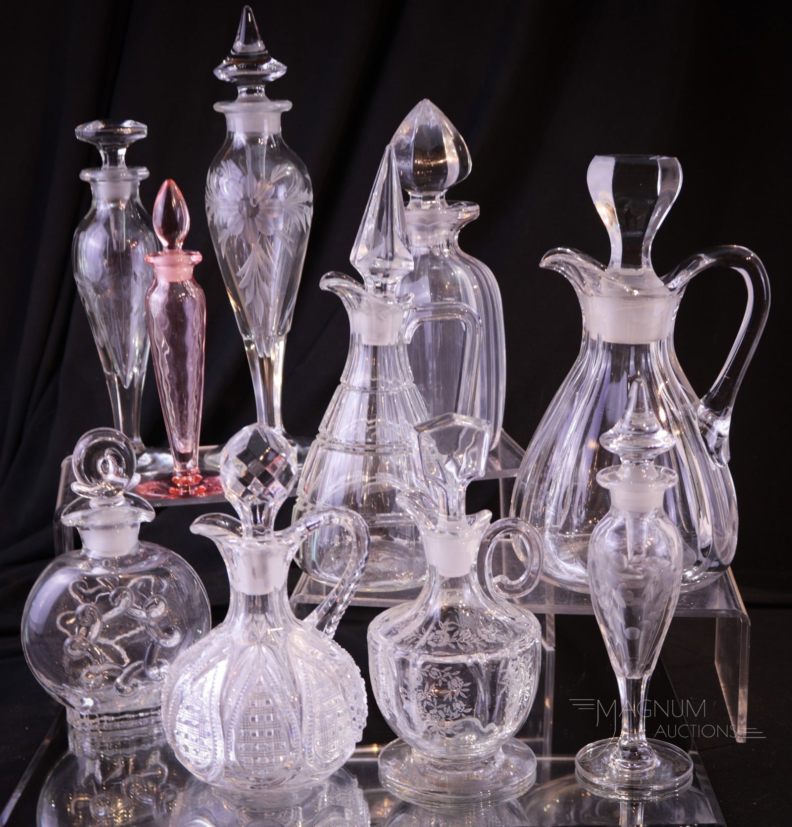 10 pc Lot Heisey Glass Perfumes & Cruets: Ten assorted finds in Heisey glass in the form of cruets and perfumes. One of the perfumes is in flamingo coloring. Tallest measures 9 1/2".