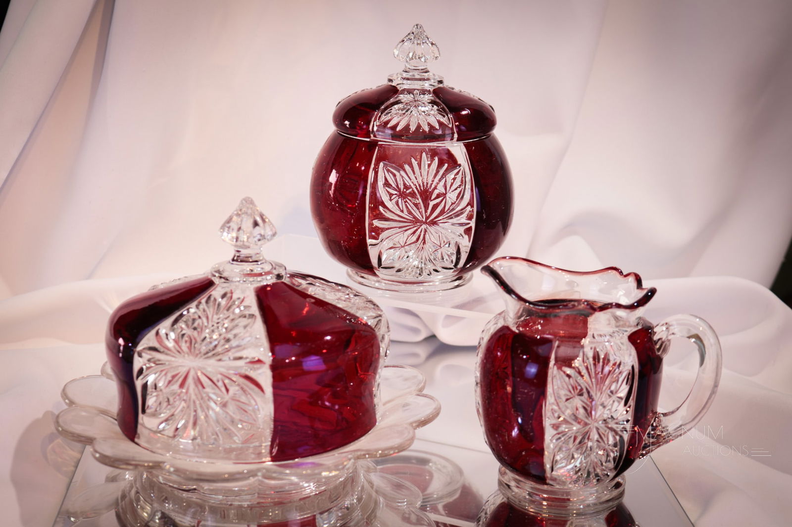 3 pc Lot Riverside Brilliant Ruby Stained Glass: Three selections in ruby stained Riverside glass sure to be collection enhancing. Included in the lot is a covered butter, creamer, and covered sugar bowl. Tallest measures 6". Provenance: This item
