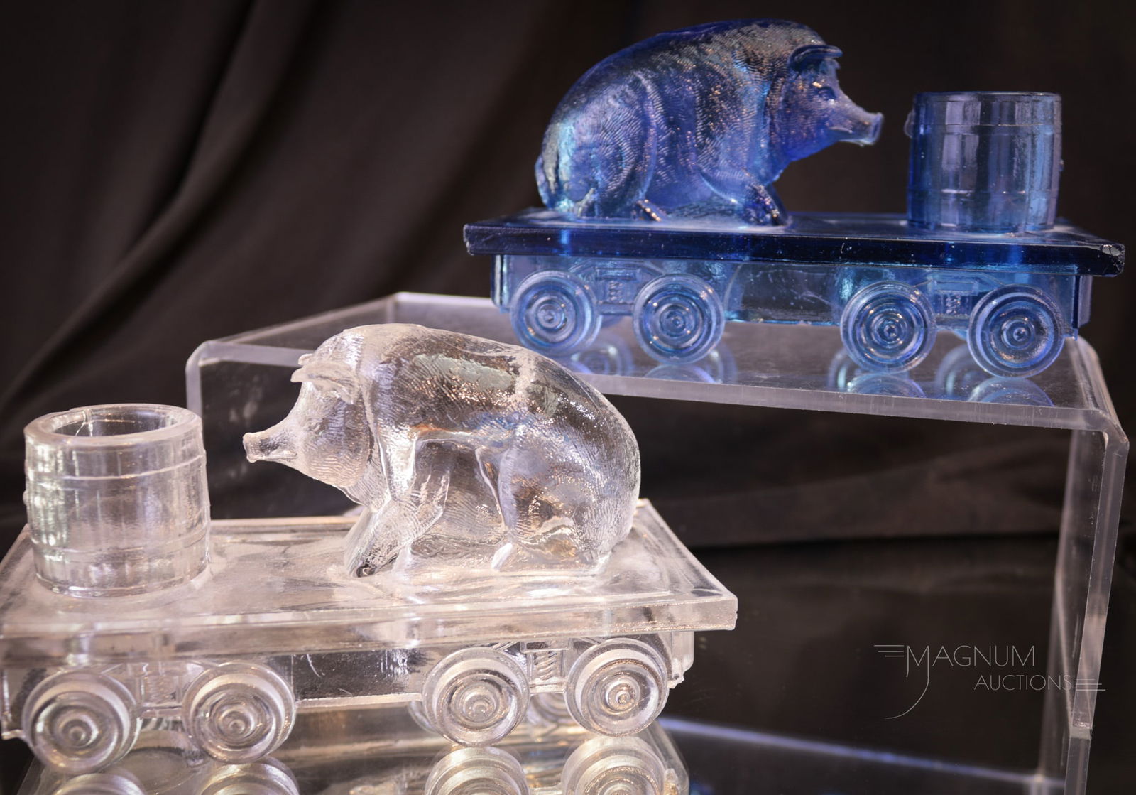 2 pc Lot Bellaire Goblet Co. "Pig on a Flat Car" Toothpick Holders: Two colors of the popular Bellaire Goblet Co. "Pig on a Flat Car" toothpick holder. One in clear and one in blue Each measures 3" tall. Blue with minor roughness possibly as-made to all four corners o