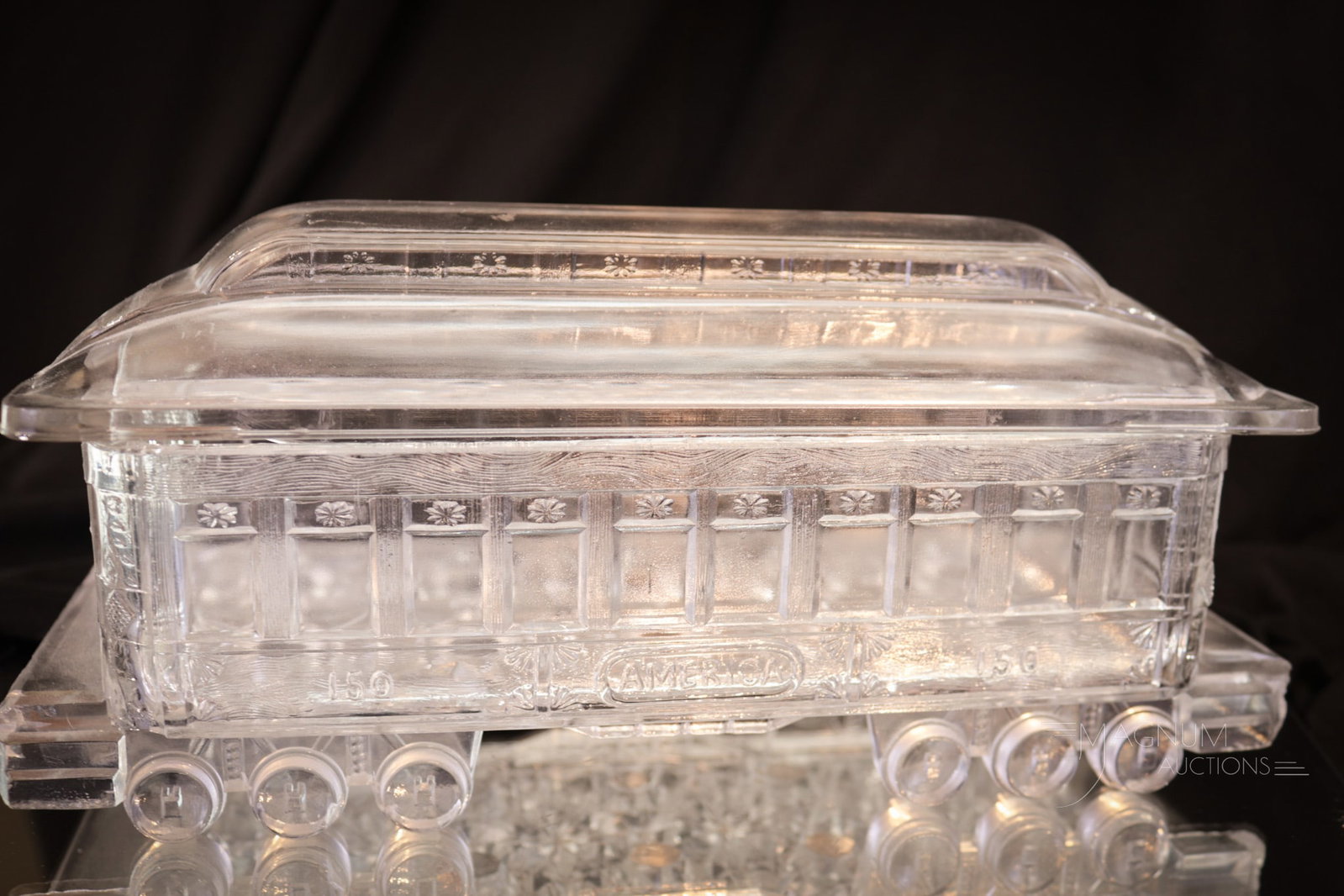 Pullman "America" Clear Covered Glass Train Car: Seldom seen example of a Pullman "America" Victorian glass train car. Car measures 3 1/2" tall, 9 1/2" wide. A chip is noted to the handle of the cover. Possibly as-made roughness to base rim. Provena